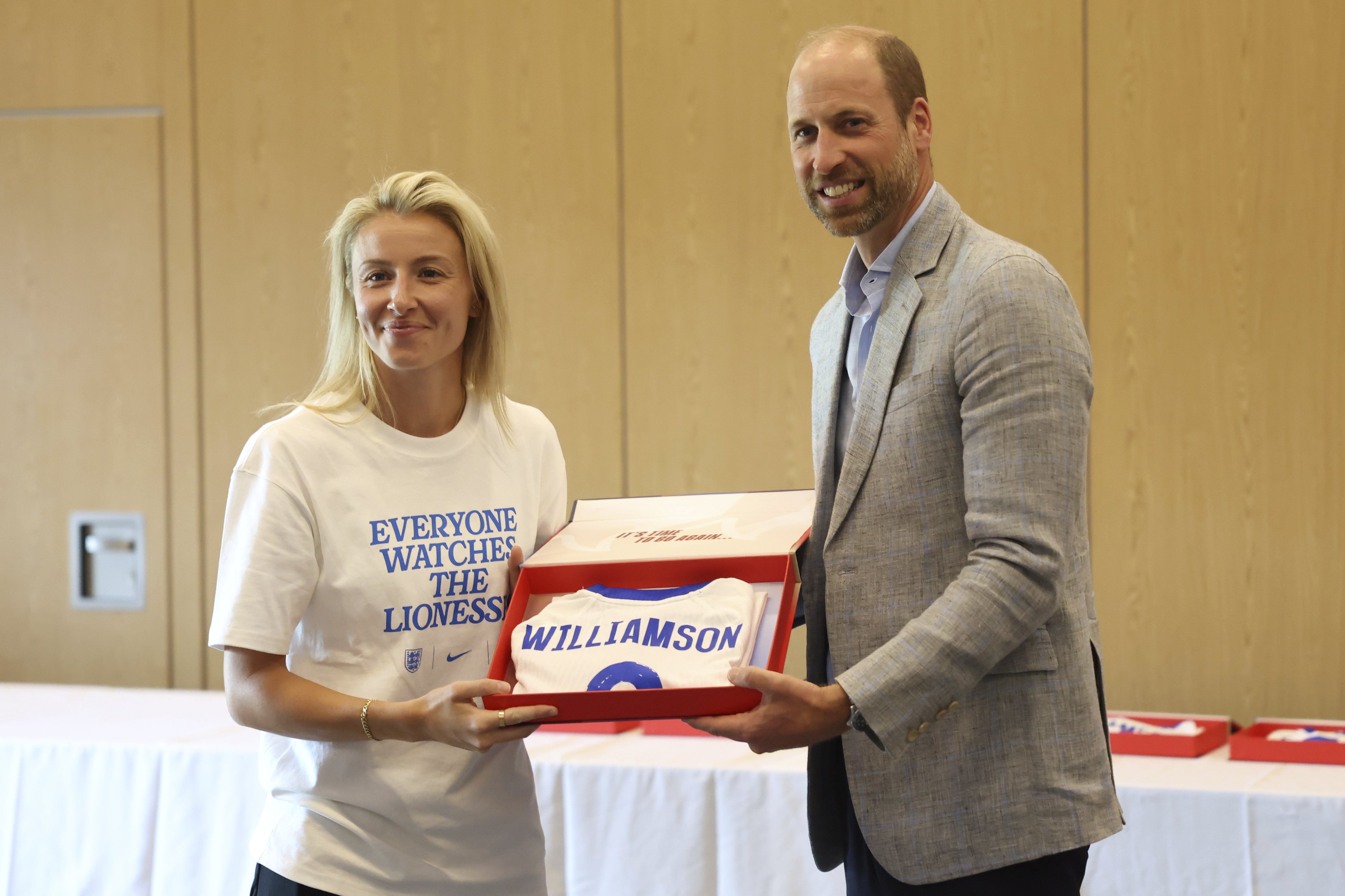 The Prince of Wales hands over a shirt to Lioness Leah Williamson during the visit