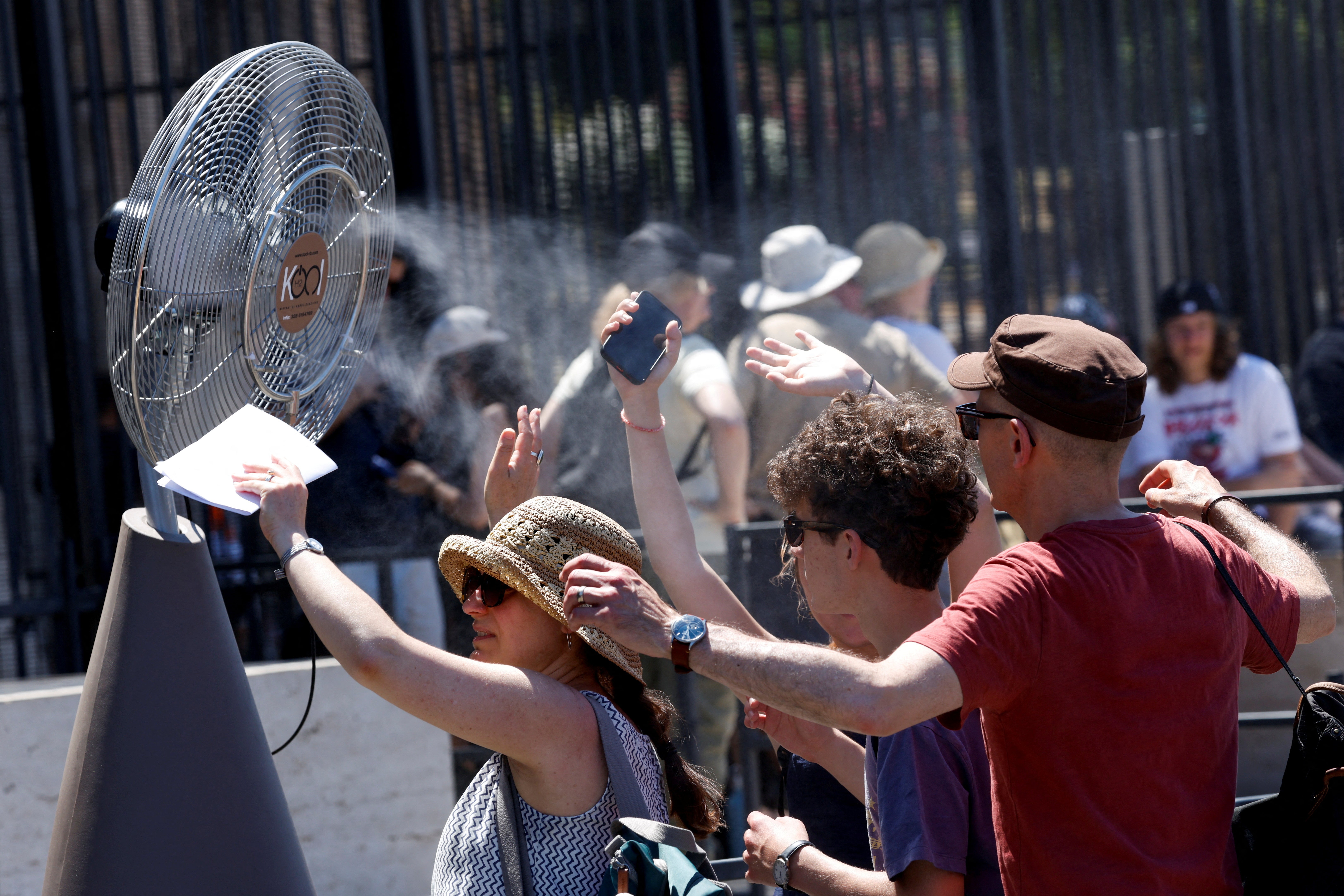 Tourists stand in front of a cooling fan installed outside the Colosseum in Rome on Monday