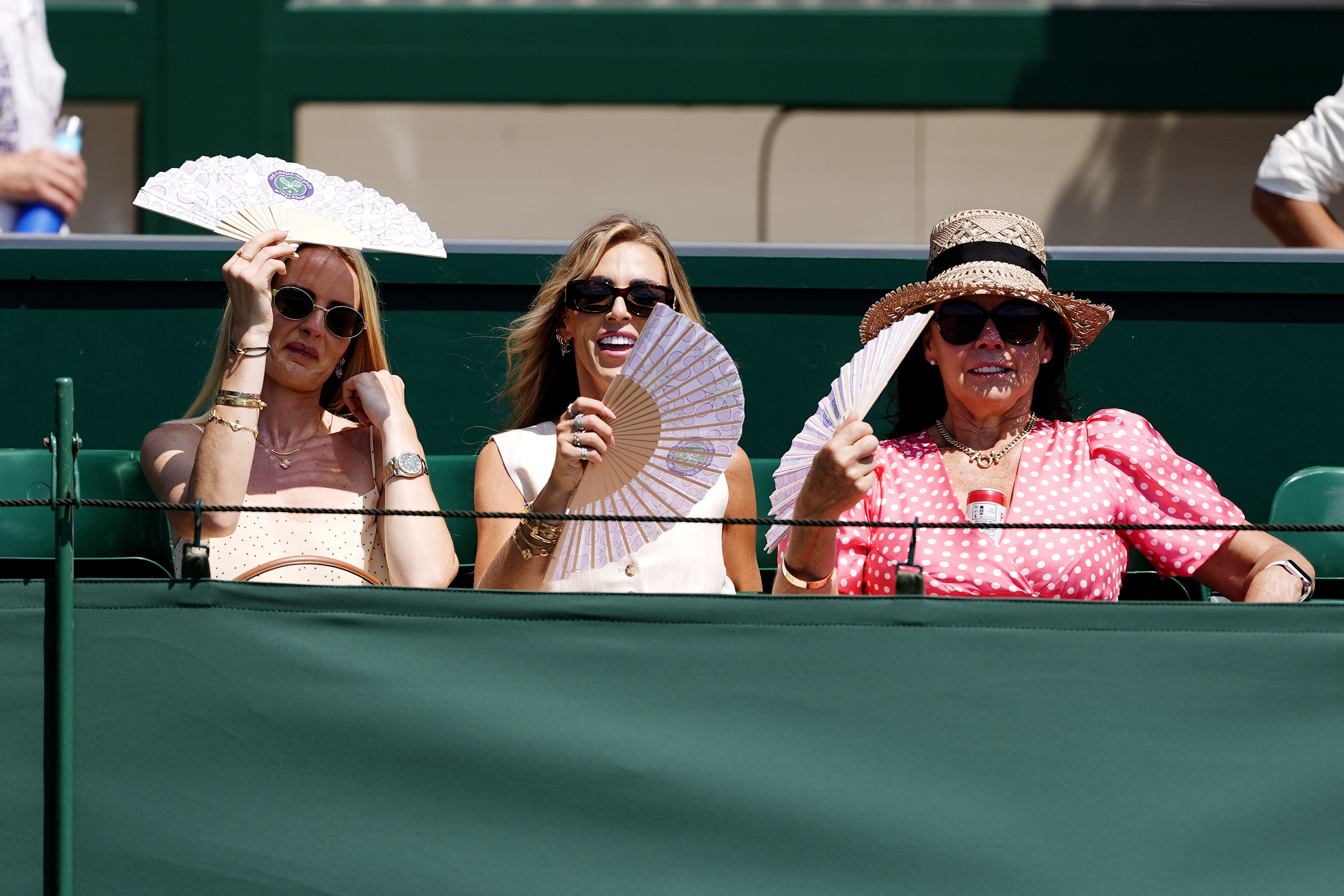 Spectators use fans to cool down on day one of the 2025 Wimbledon Championships at the All England Lawn Tennis and Croquet Club (Jordan Pettitt/PA)