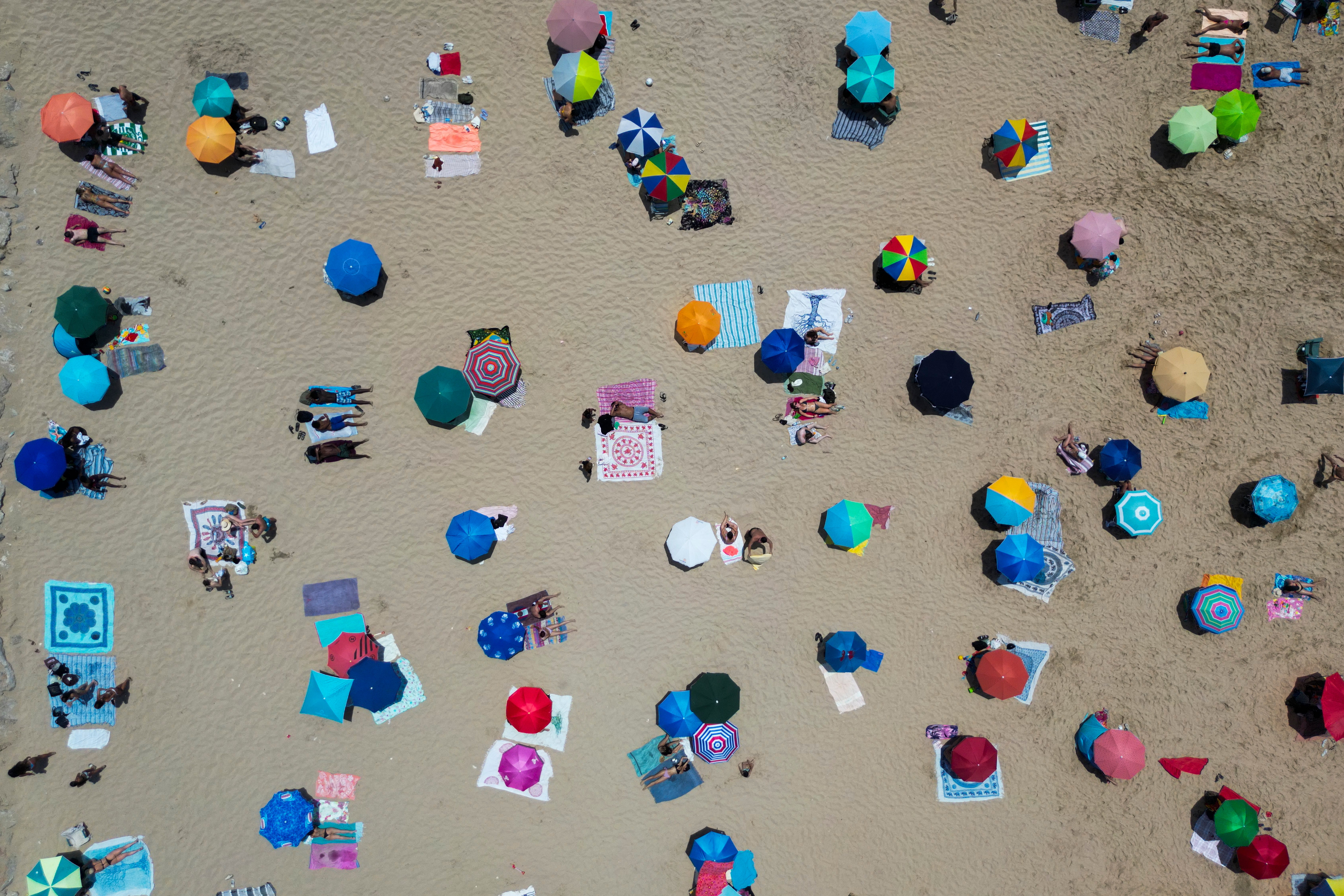 People sit under umberllas at the Costa da Caparica beach in Almada, near Lisbon on Sunday