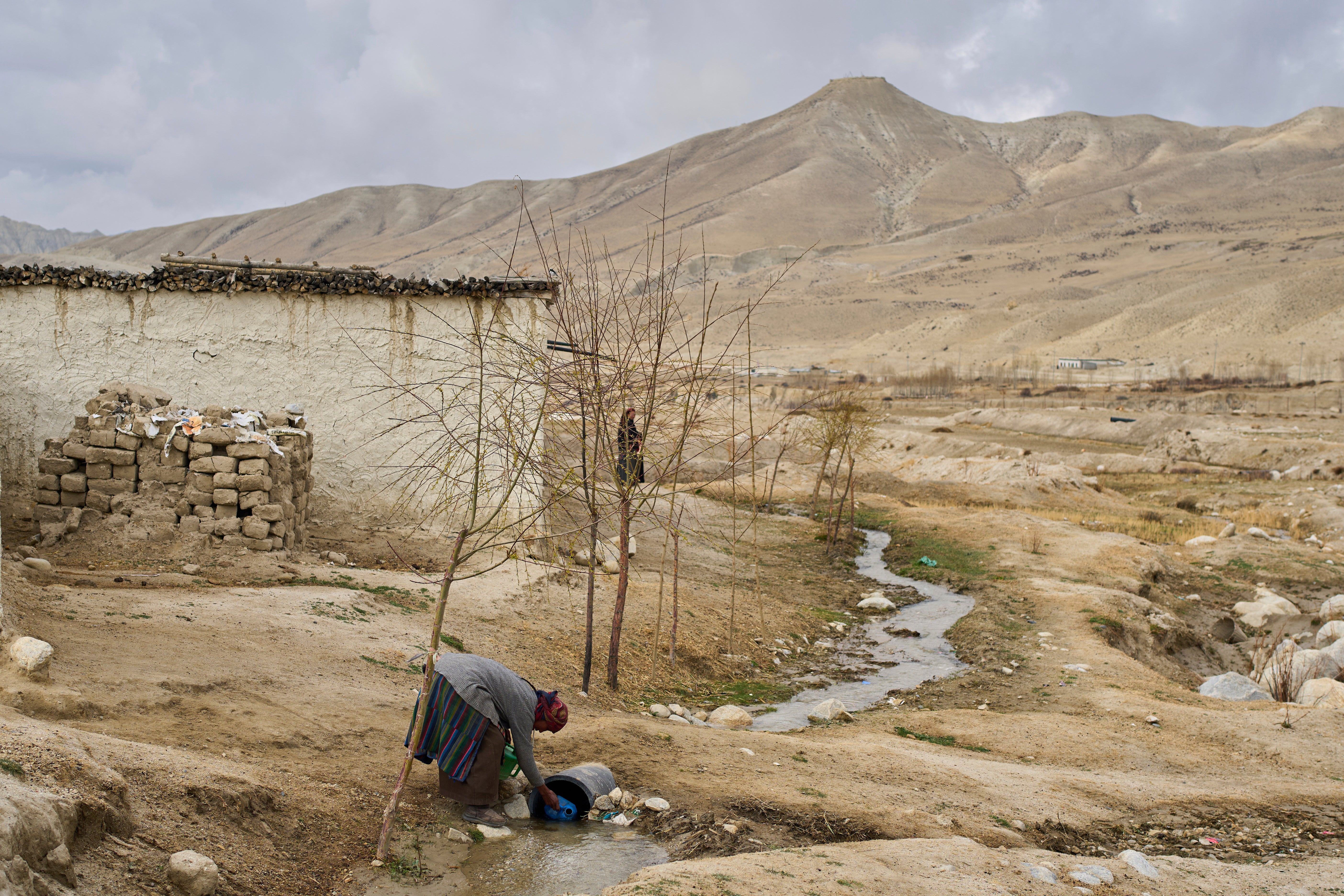 A woman collects water at the newly relocated settlement of the abandoned Samjung village in the Mustang region, 462 kilometers (288 miles) west of Kathmandu, Nepal, Saturday, April 19, 2025. (AP Photo/Niranjan Shrestha)
