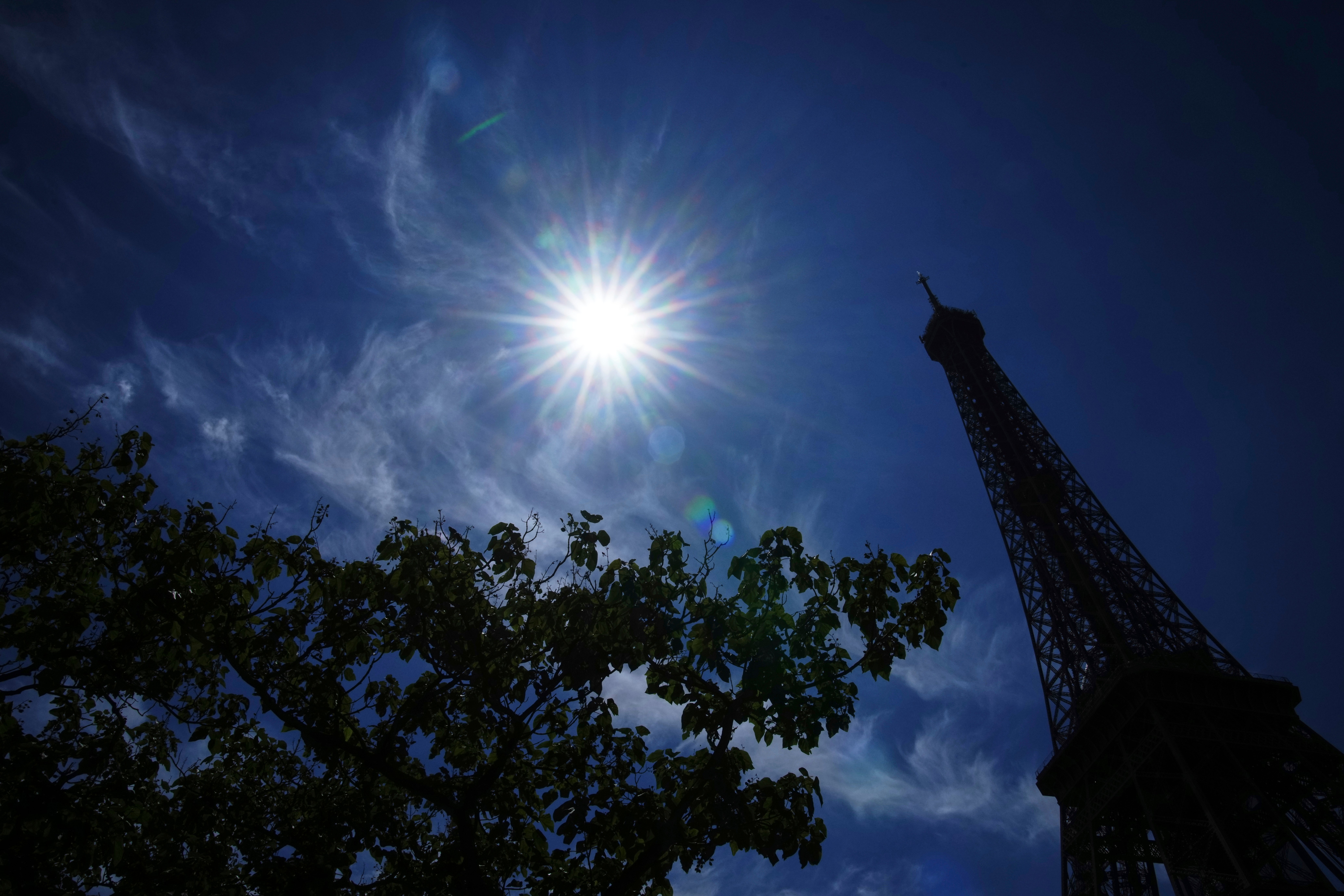 The sun shines over the the Eiffel Tower during a heat wave, Monday, June 30, 2025 in Paris. (AP Photo/Christophe Ena)