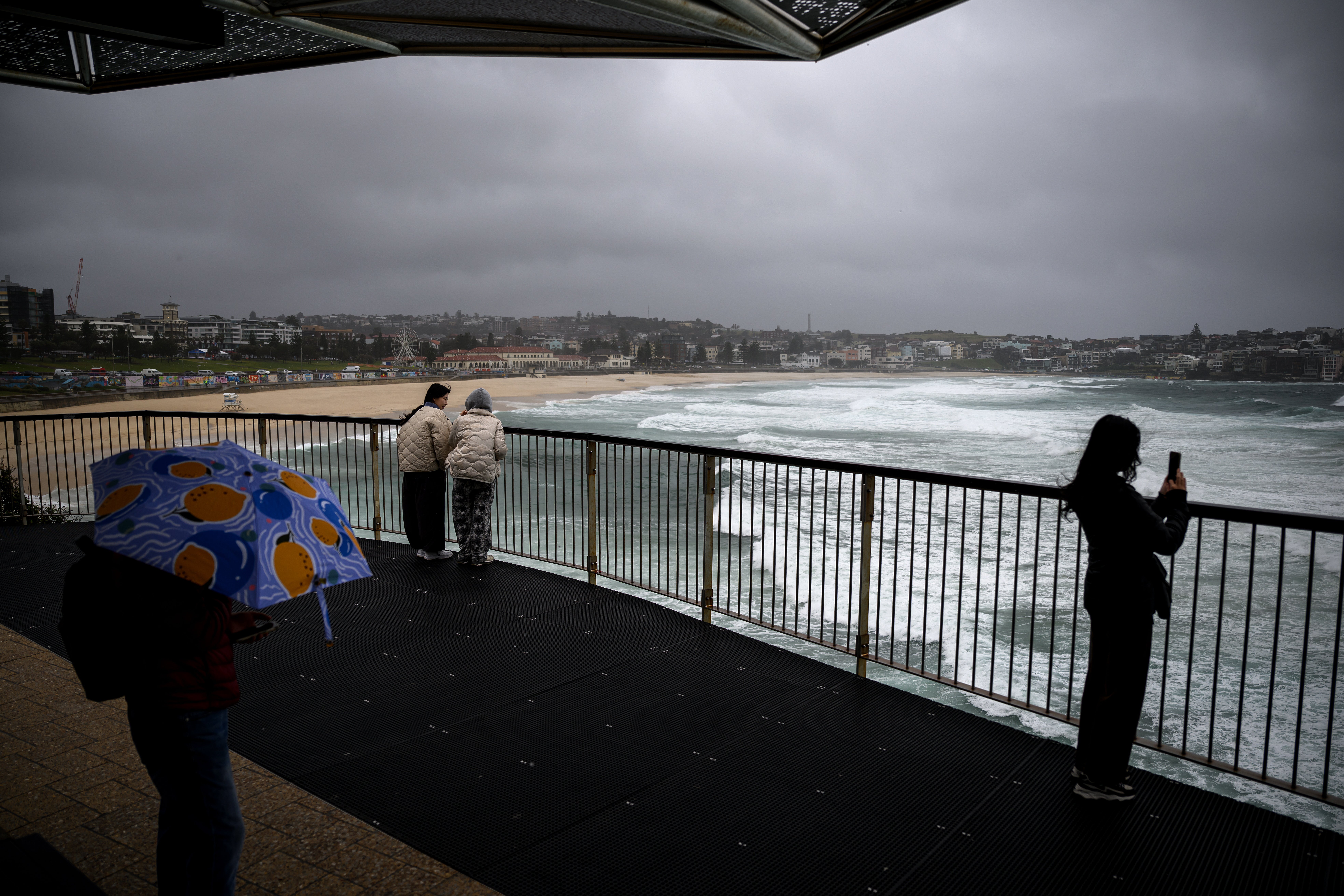 People watch large swells at Bondi Beach in Sydney, Australia
