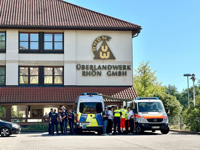 <p>German police and emergency services stand on the premises of a regional grid operator following the stabbing attack</p>