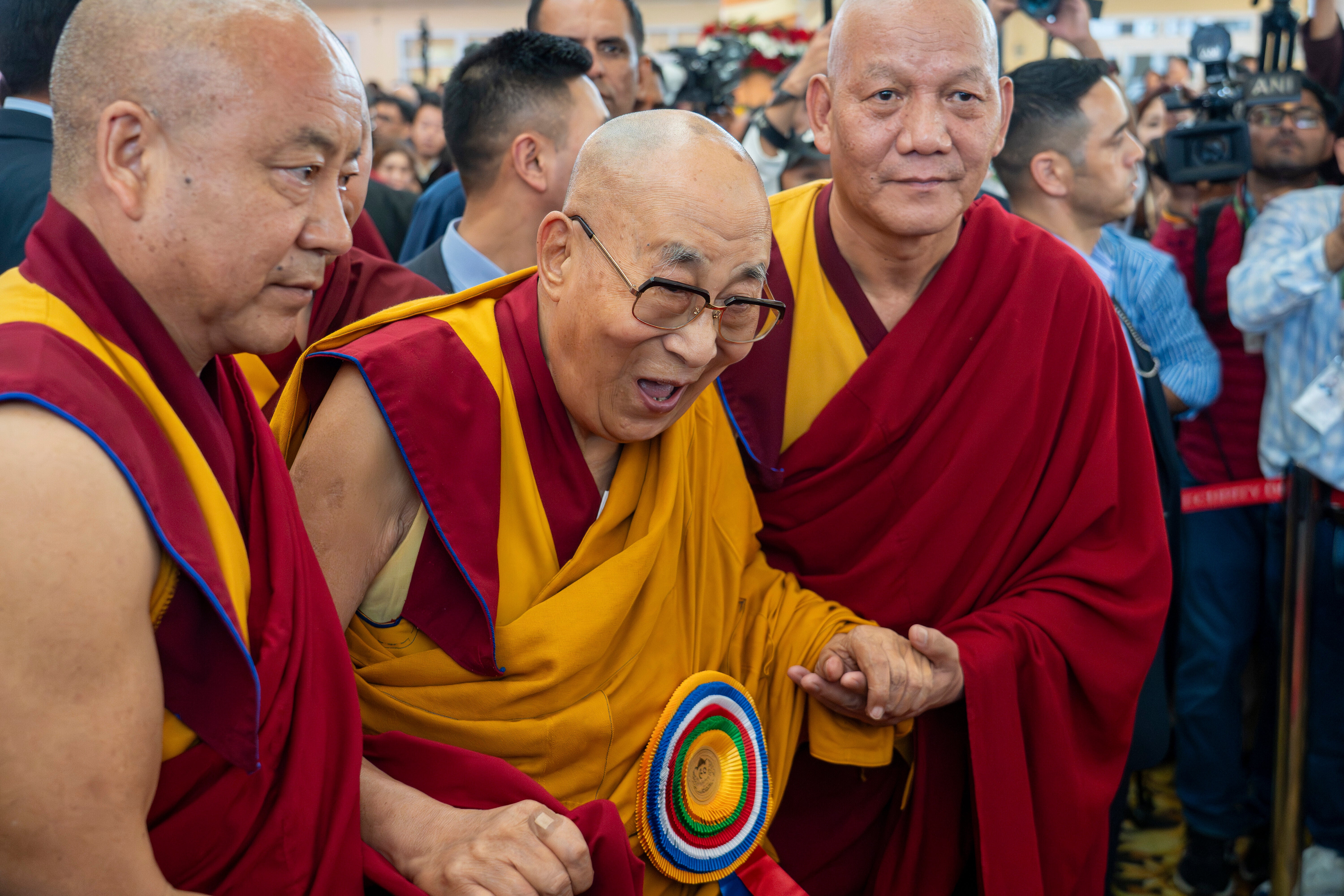 Monks assist the Tibetan spiritual leader the Dalai Lama after he presided over an event to celebrate his 90th birthday