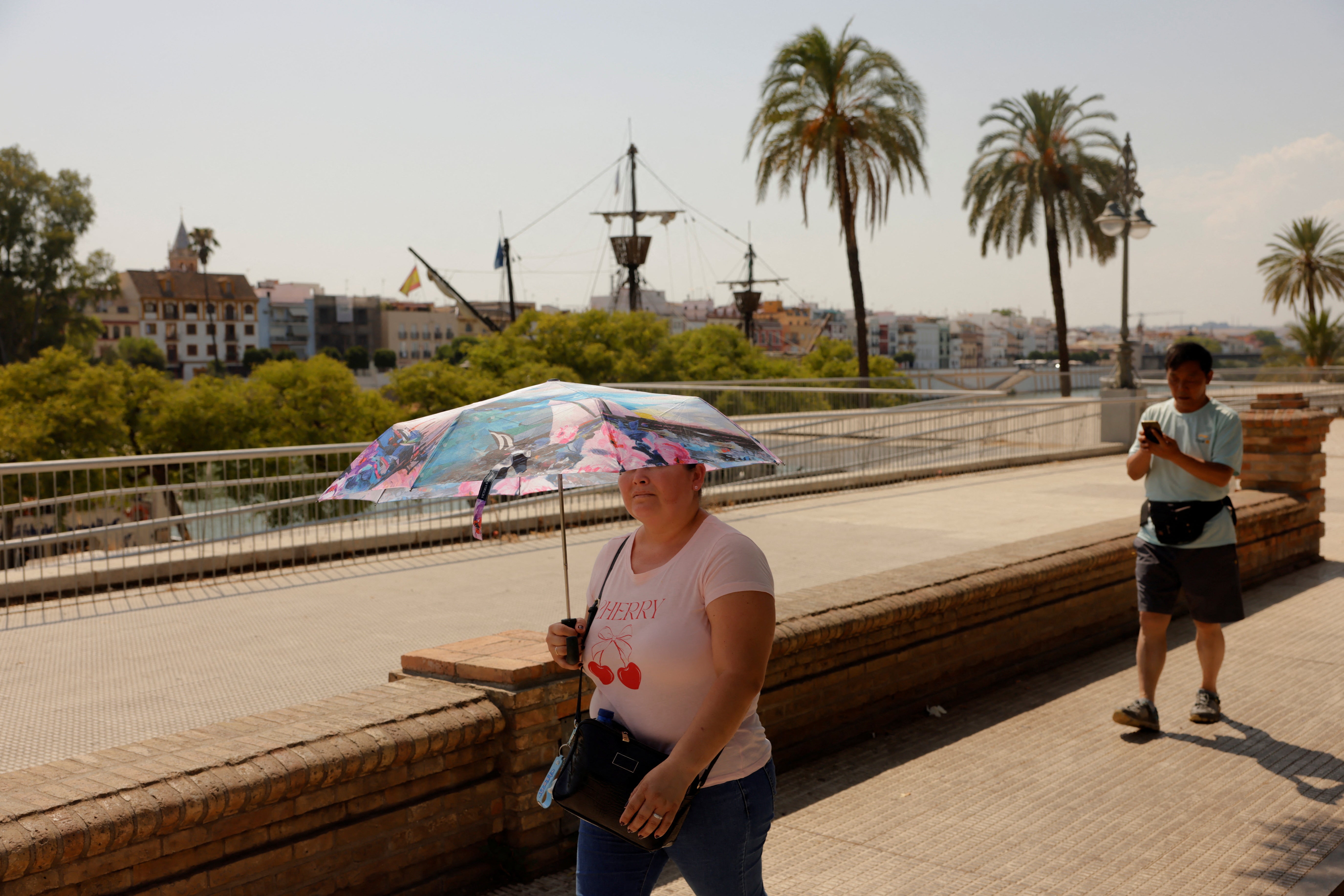 A woman holds an umbrella to shield herself from the strong sun during a heatwave in Seville, Spain