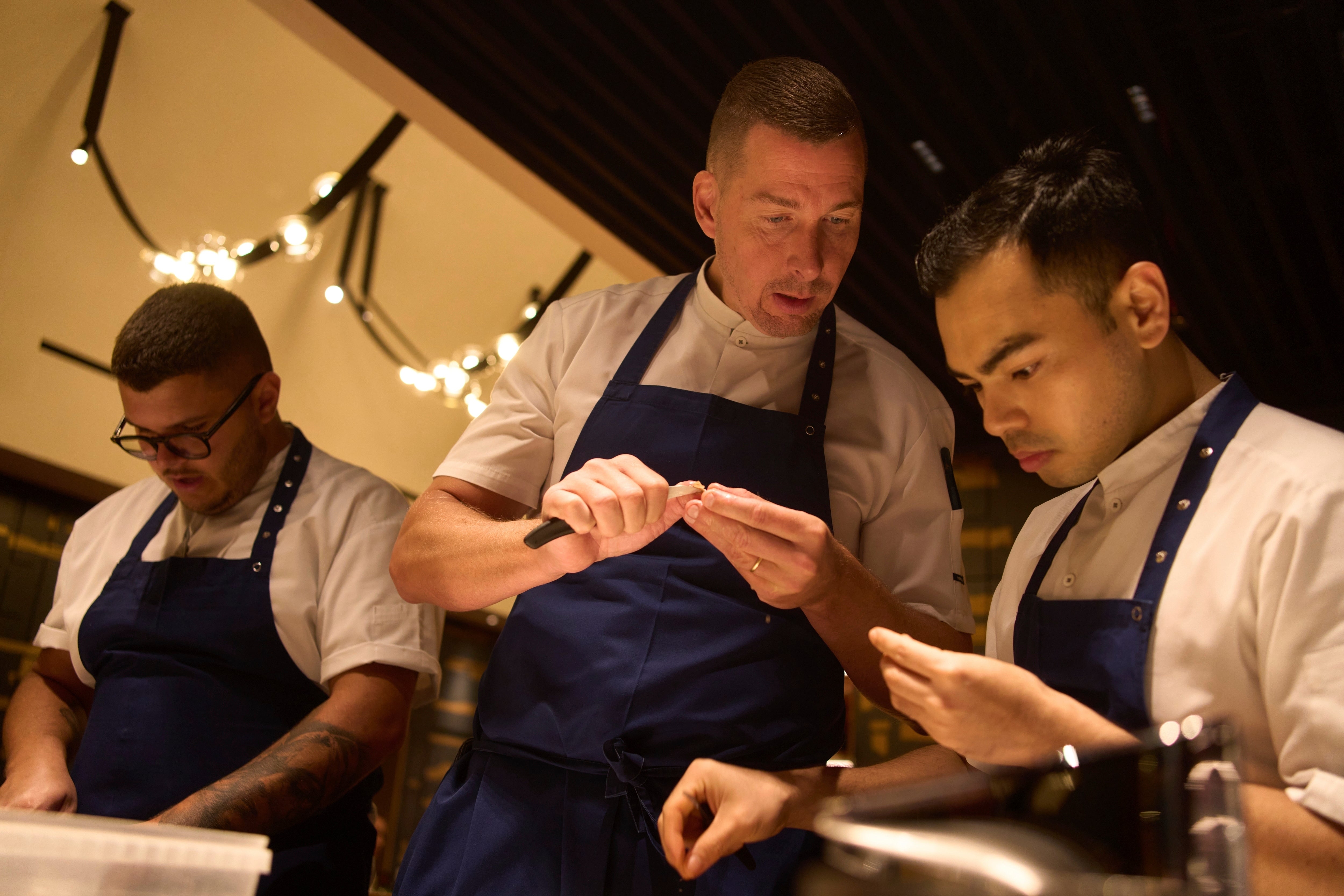 Executive chef Torsten Vildgaard, center, and his staff chop nuts at FZN Restaurant on Palm Jumeirah in Dubai, United Arab Emirates, Friday, June 13, 2025. (AP Photo/ Fatima Shbair)
