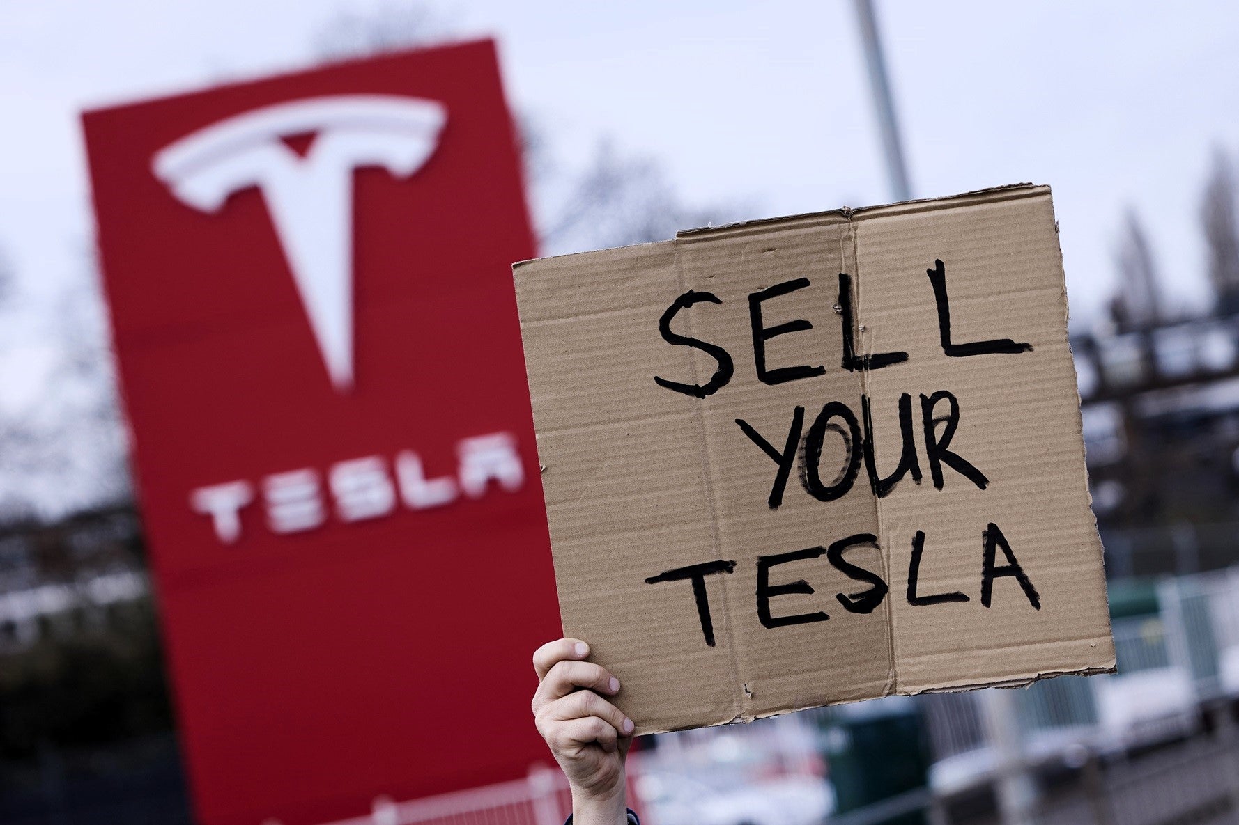 A home-made sign is held up at a protest outside a Tesla dealership in Park Royal in west London on 22 March, 2025