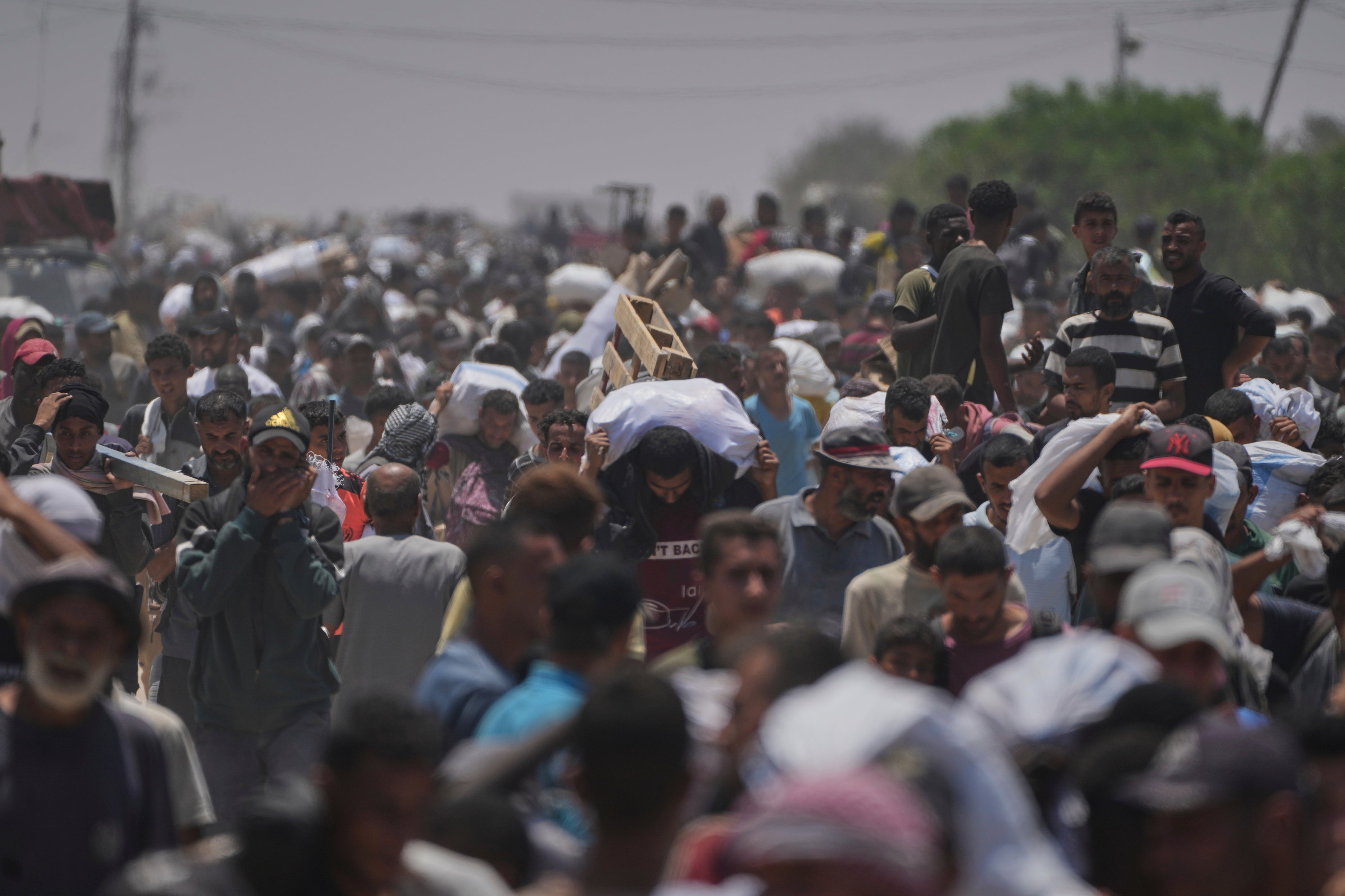 Palestinians carry bags containing food and humanitarian aid packages delivered by the Gaza Humanitarian Foundation, a US-backed organization, in Rafah