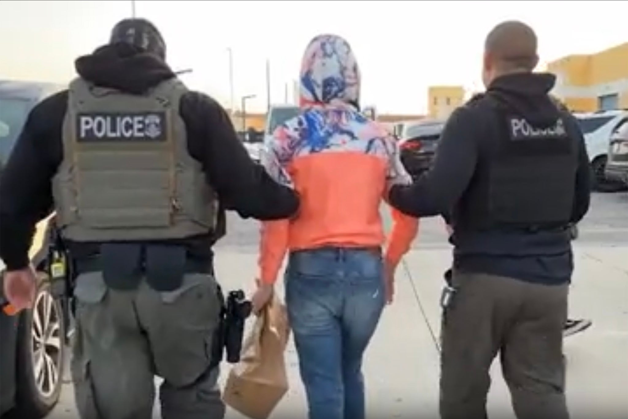 Footage from an ICE raid in May shows a woman being led away by masked agents