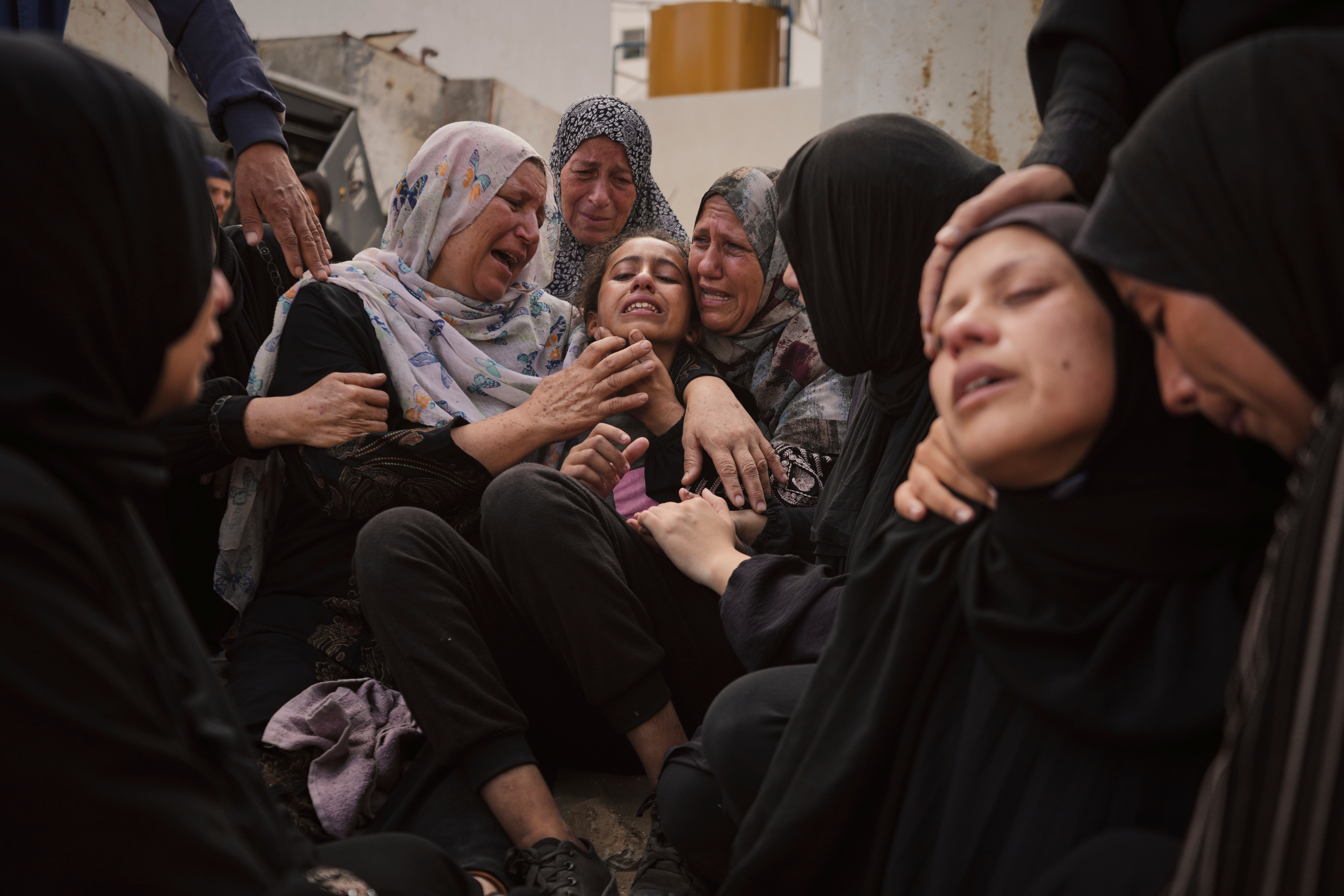 Lian Al-Za'anin, centre, is comforted by relatives as she mourns the loss of her father, Rami Al-Za'anin, who was killed while heading to an aid distribution hub, at the morgue of the Shifa Hospital in Gaza City