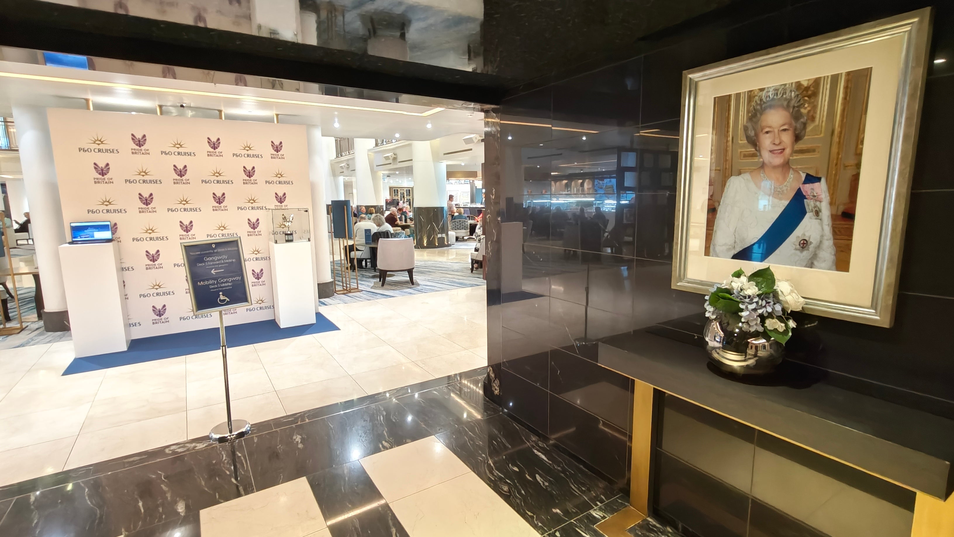A golden frame of the late Queen Elizabeth II lights up the entrance to atrium aboard Britannia