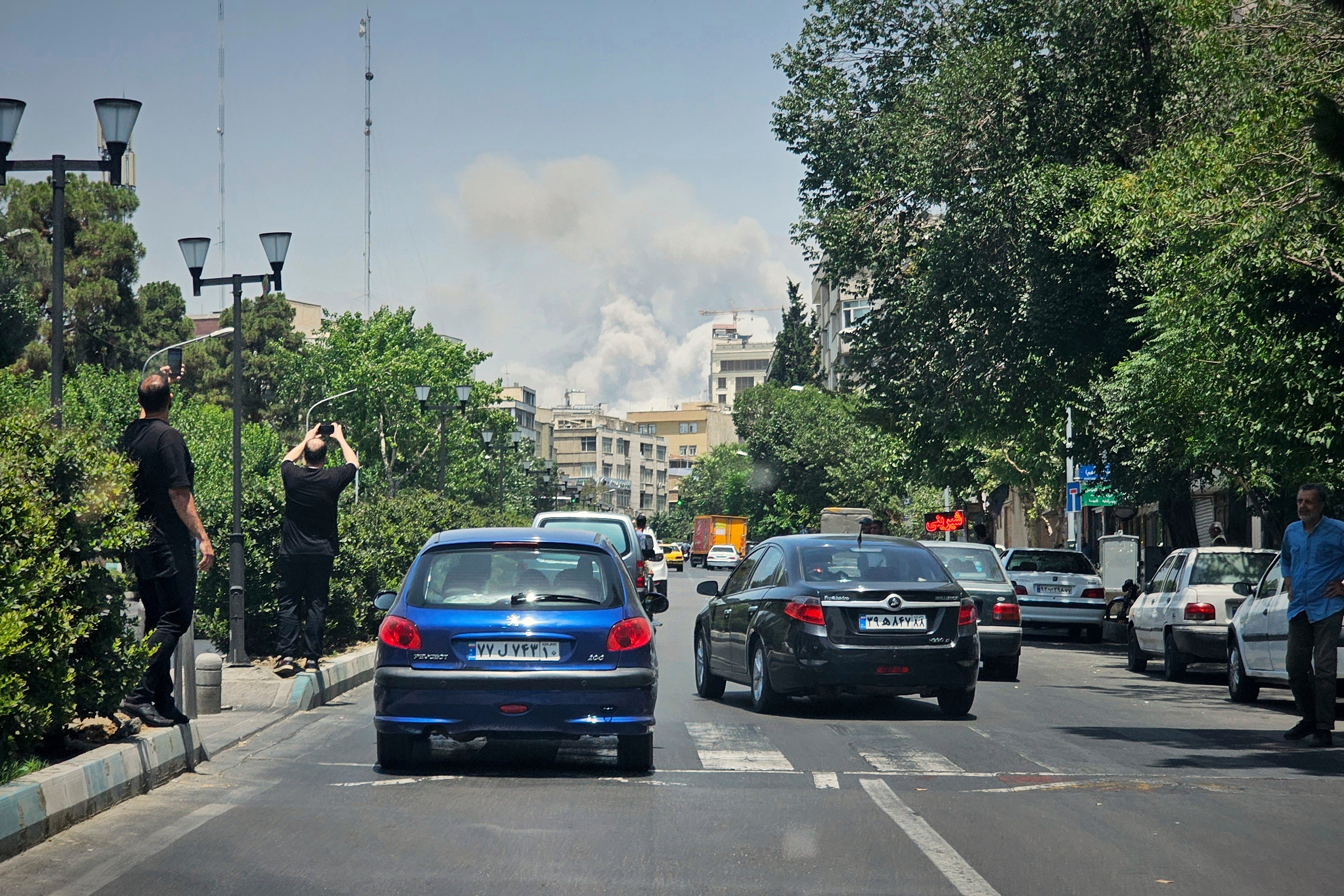 Residents take pictures of smoke rising from an Israeli strike in Tehran, Iran, Monday, June 23, 2025