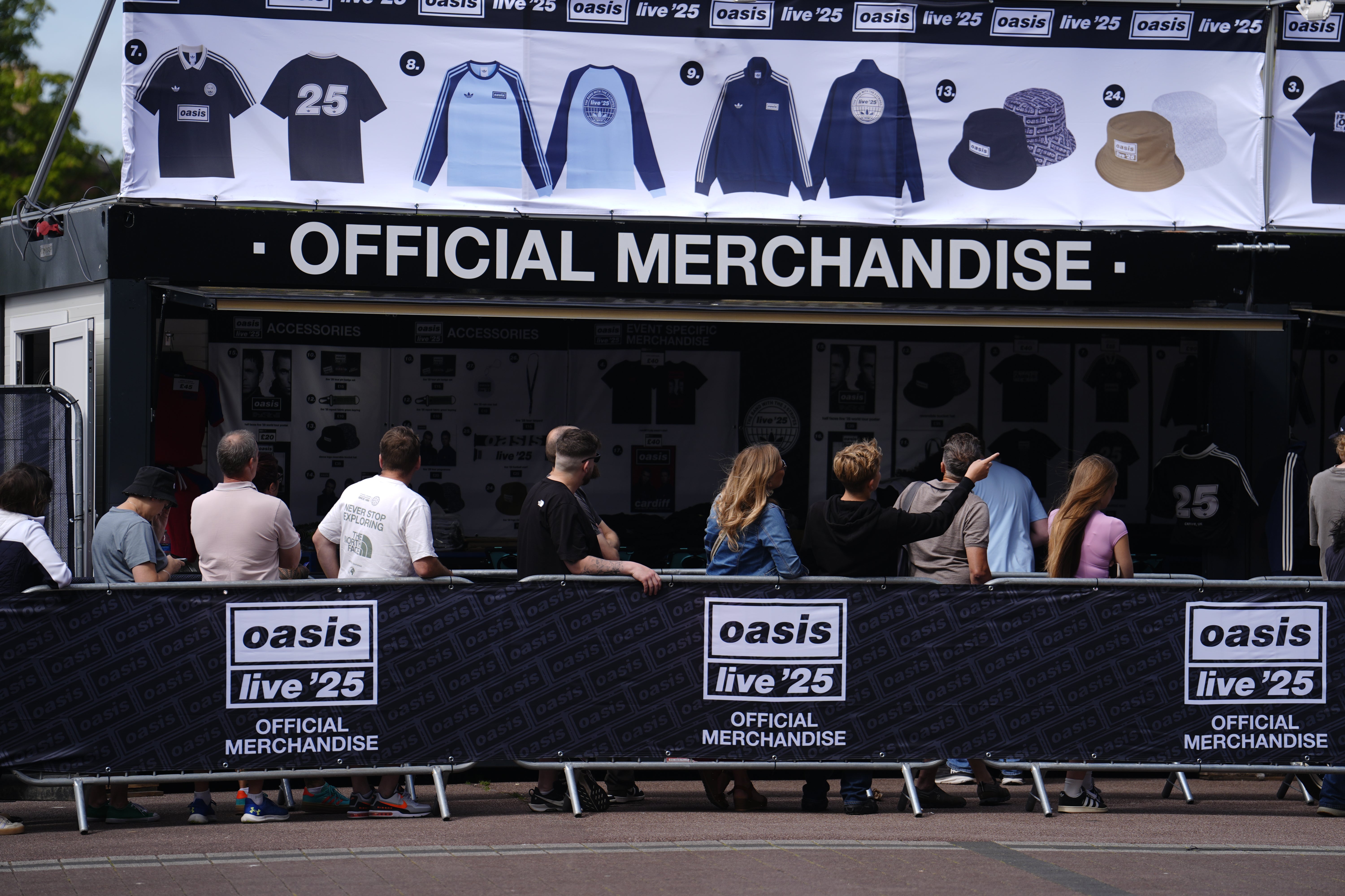 Oasis fans stand in the queue for the official merchandise stand outside the Principality Stadium in Cardiff (Jordan Pettitt/PA)
