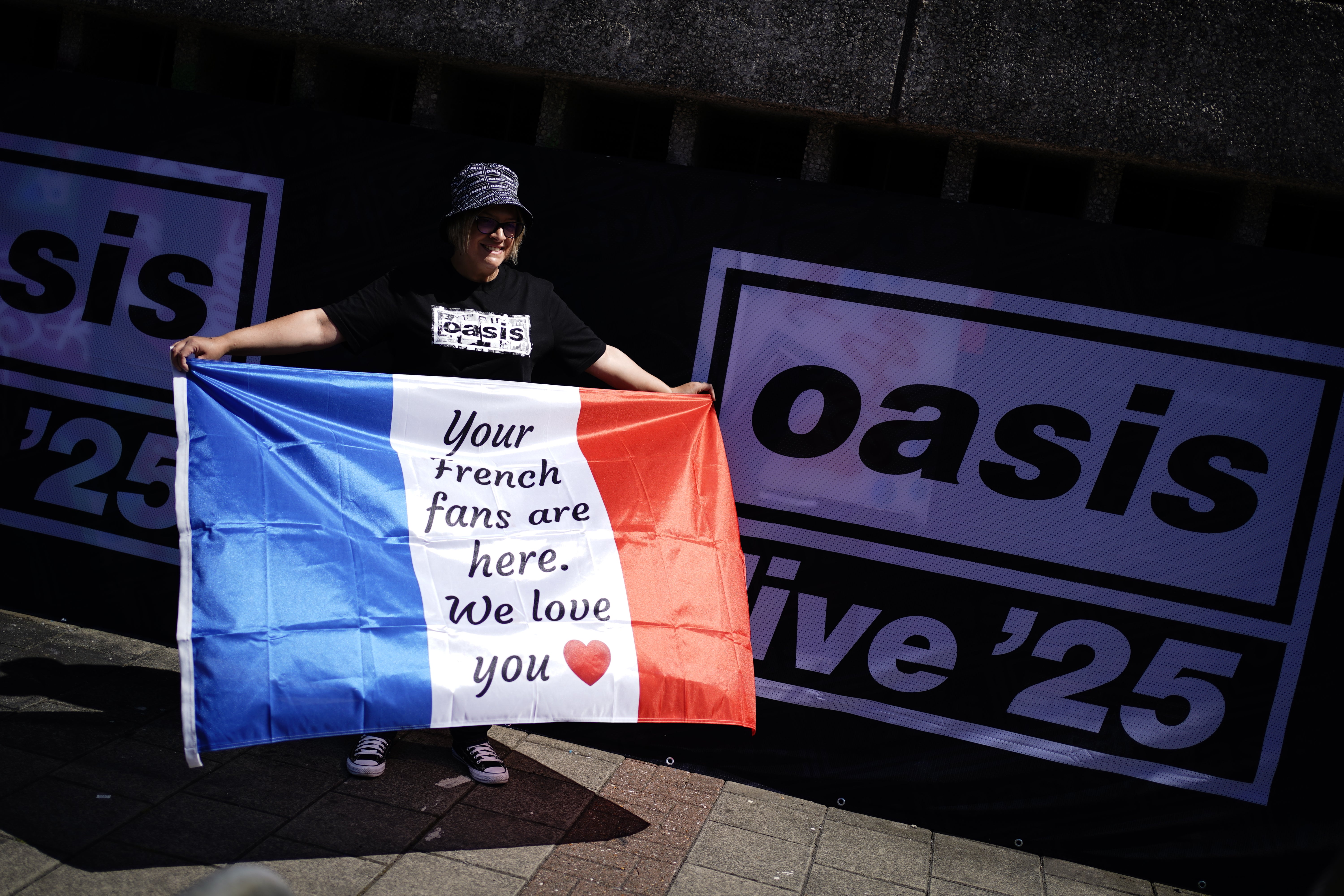 An Oasis fan from France poses for a photo outside the Principality Stadium (Jordan Pettitt/PA)