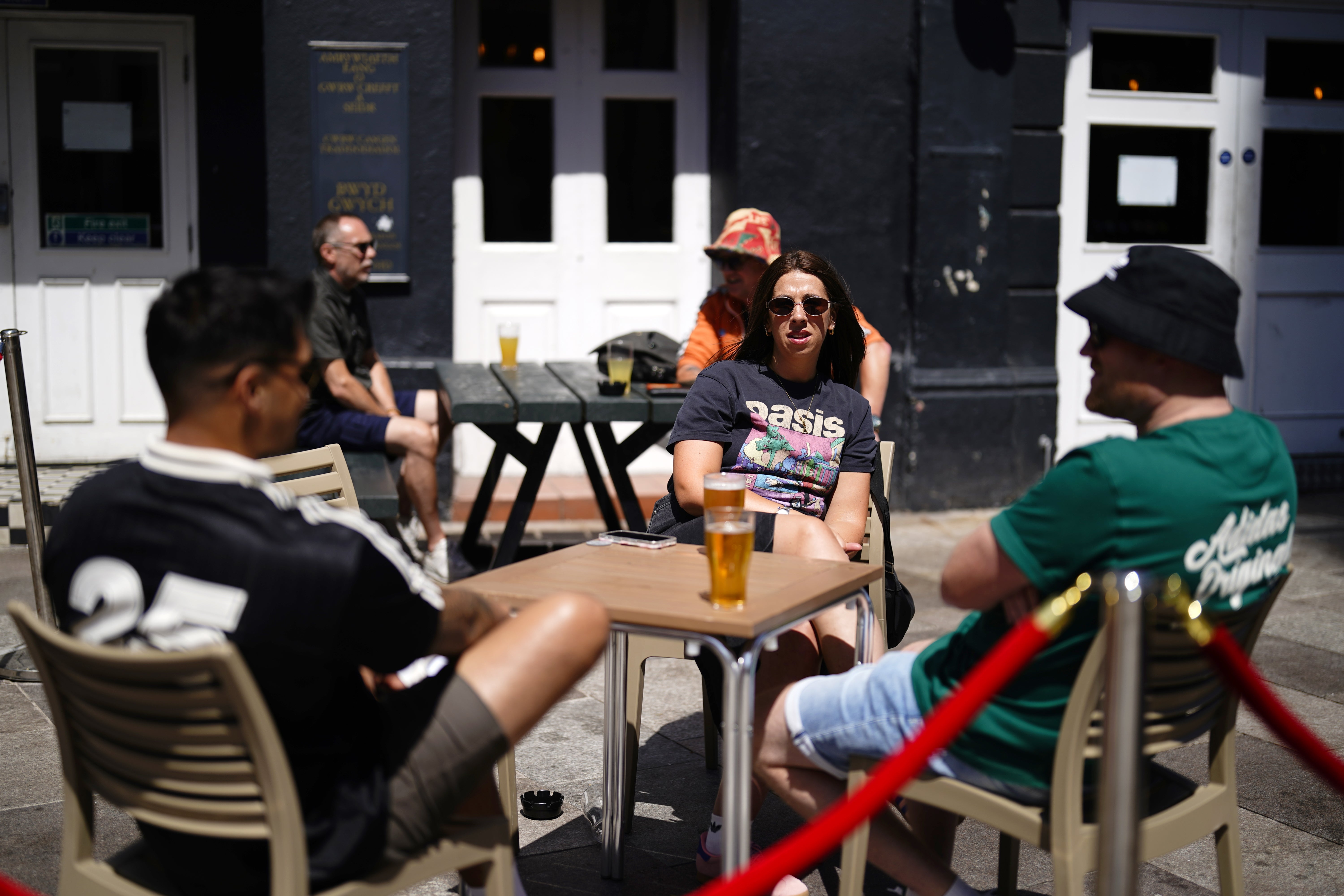 Oasis fans sitting at tables having a drink outside a pub ahead of tonight’s reunion tour opener