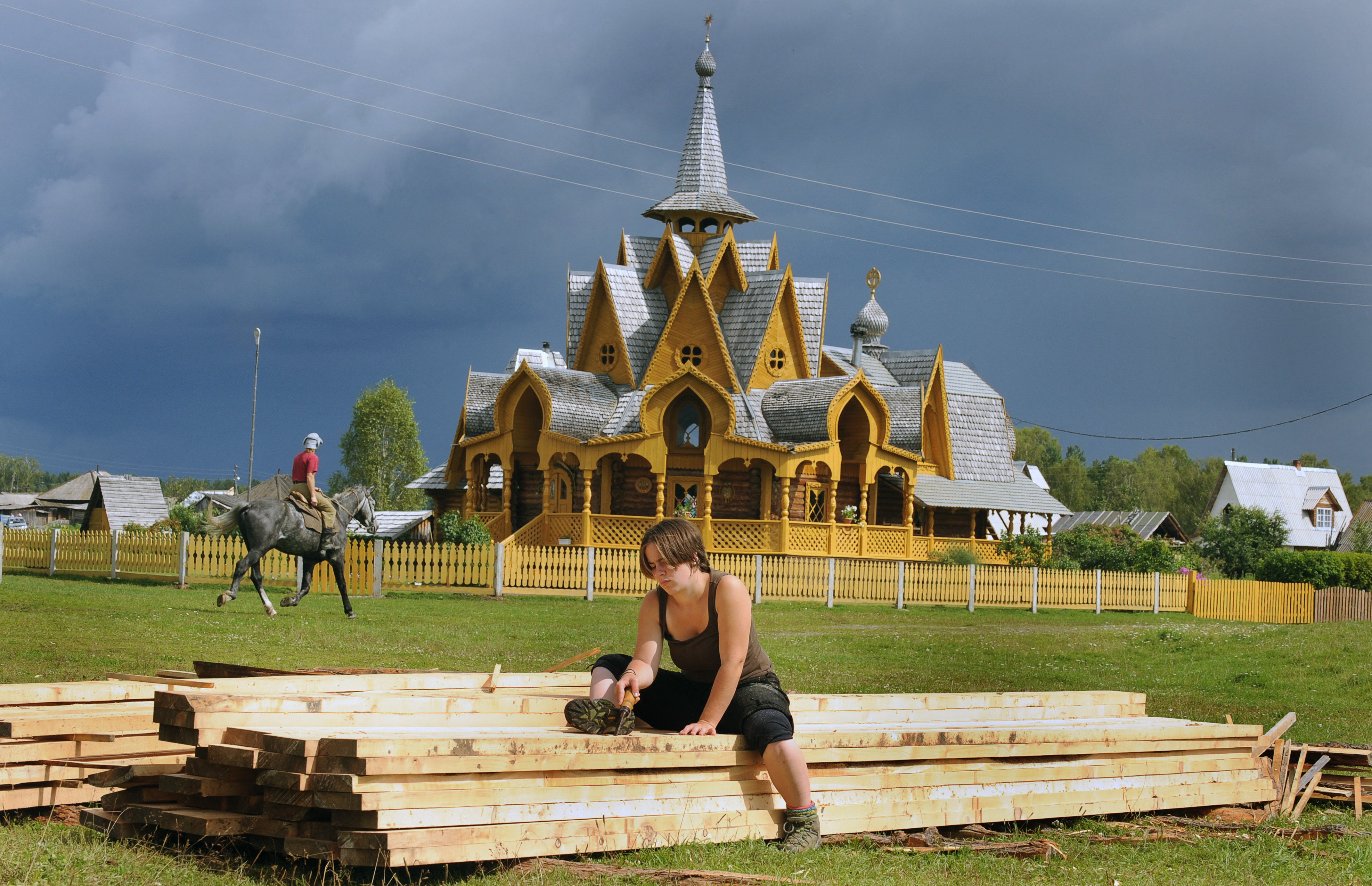 Followers work and horseback ride near a church in the remote village of Petropavlovka
