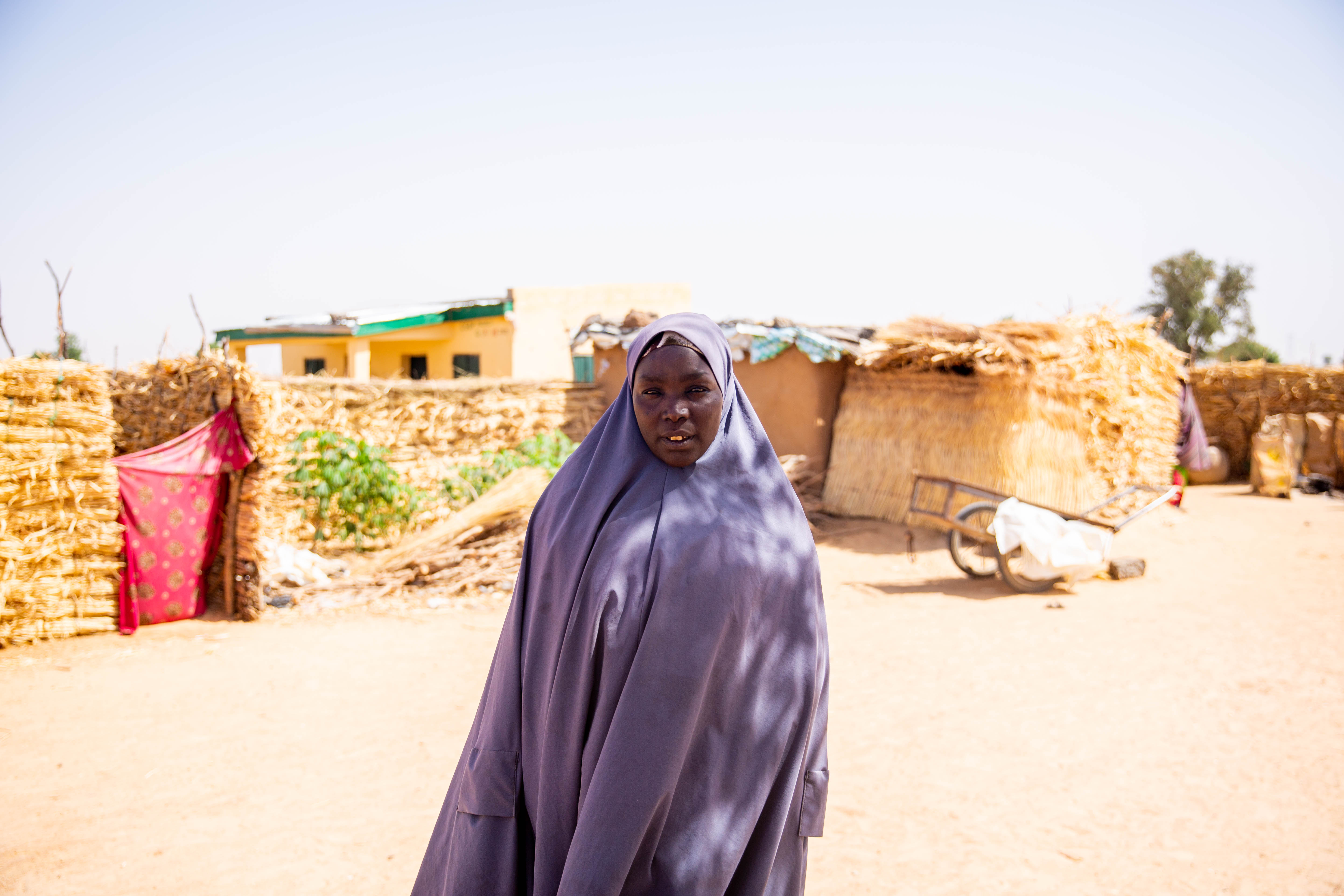 Murka, 40, a displaced mother of 10, stands outside her home in Yobe State, Nigeria