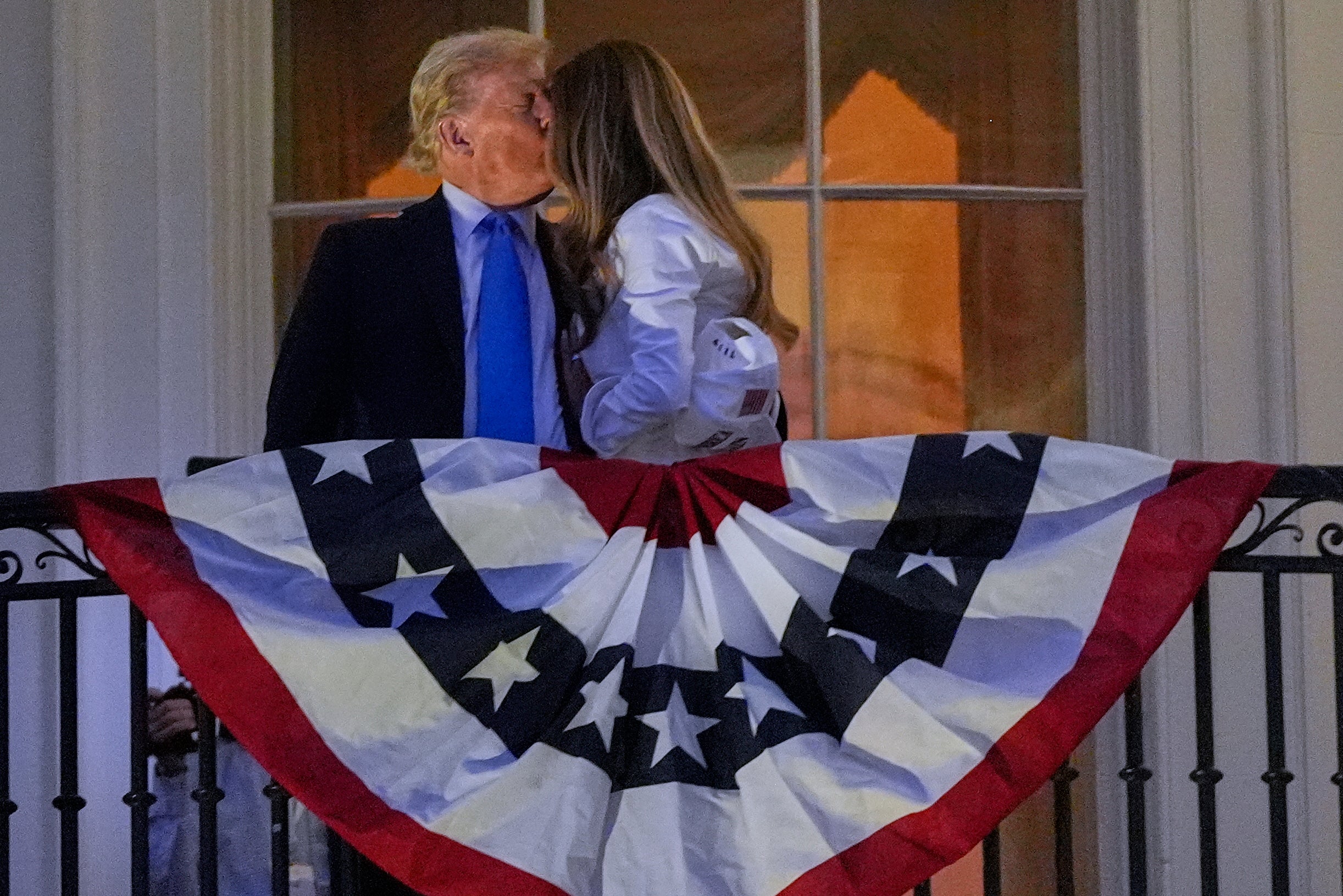 President Donald Trump and First Lady Melania Trump kiss as they watch the Independence Day fireworks show