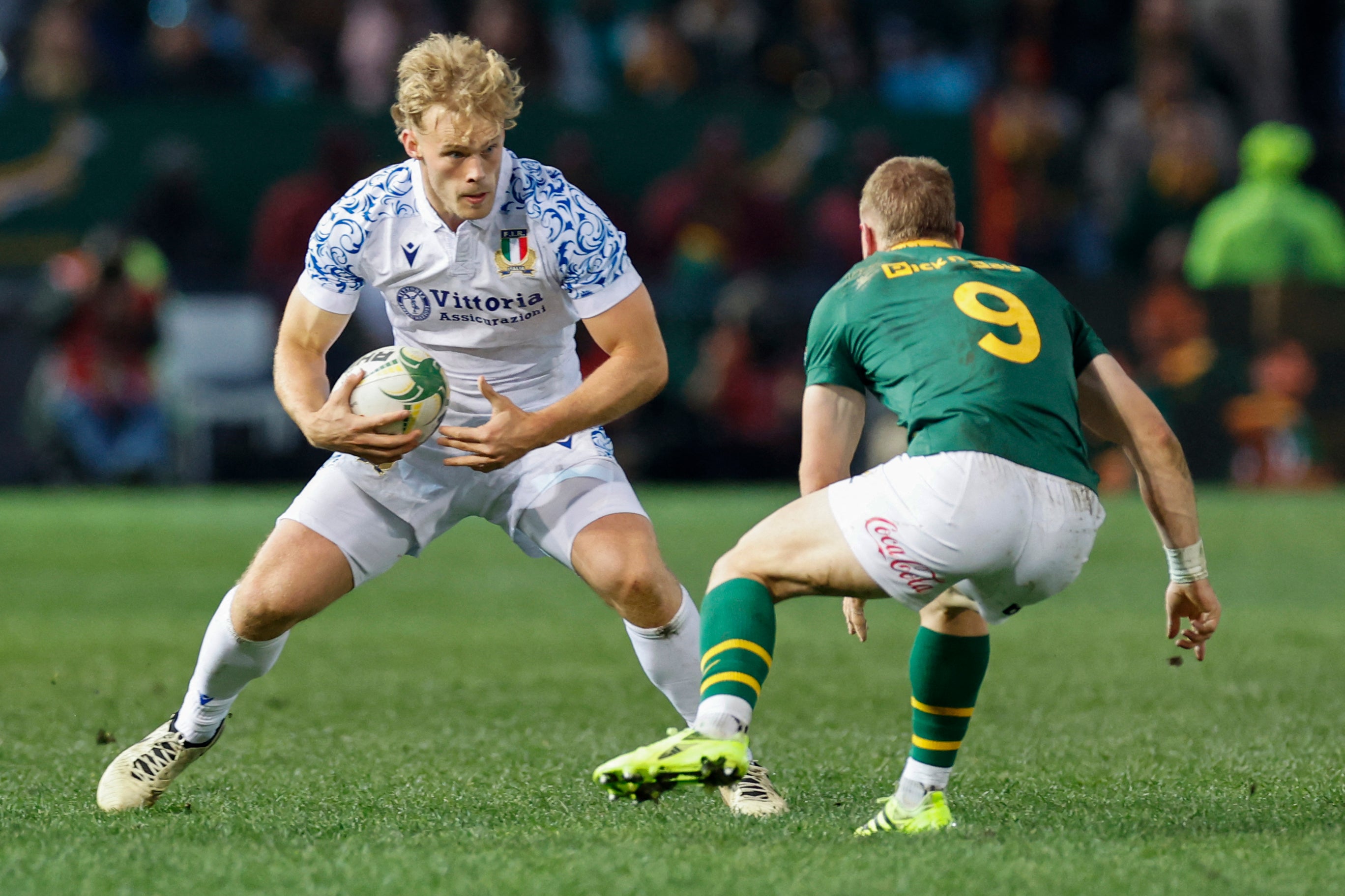 Italy's wing Louis Lynagh (L) runs with the ball.