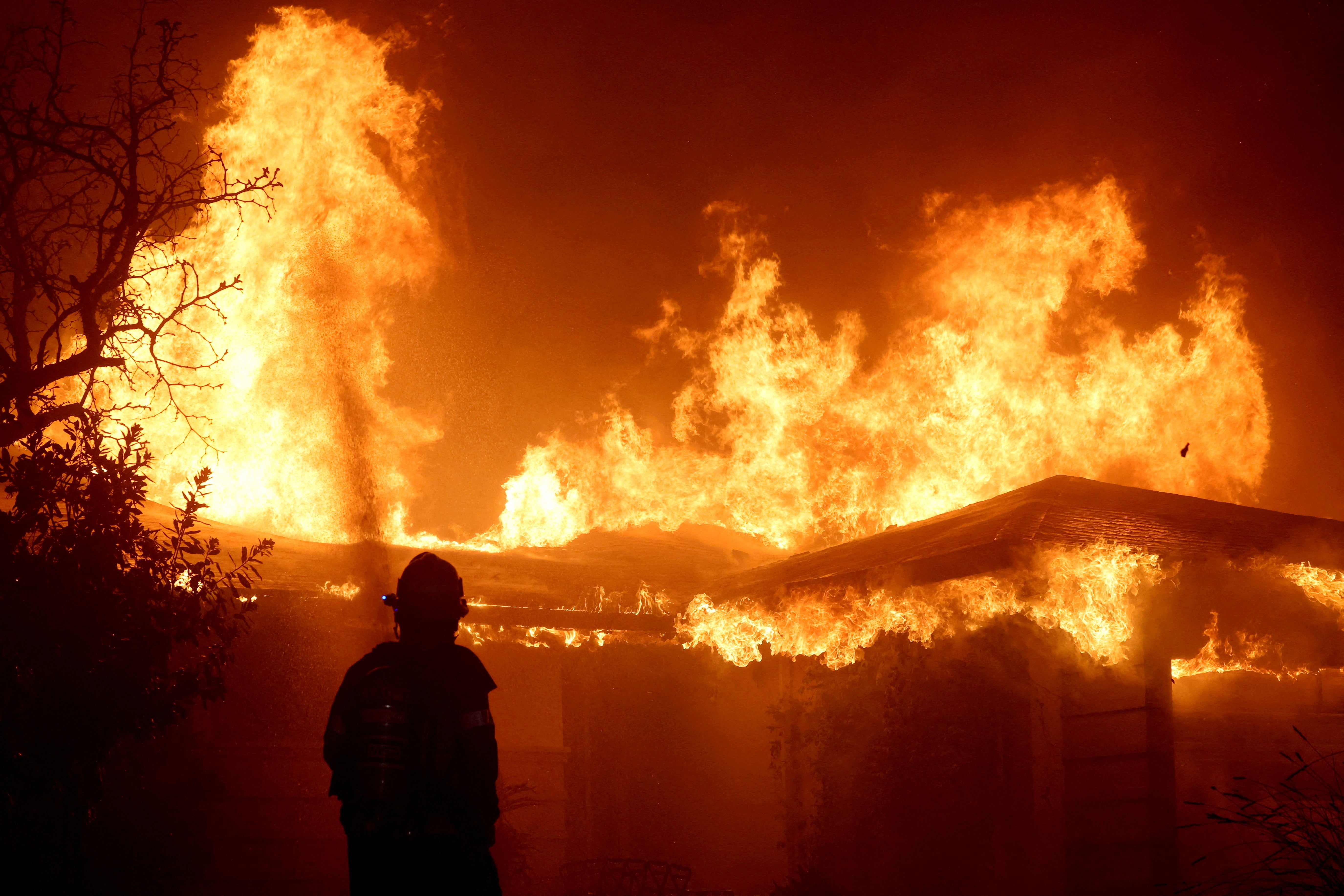 A firefighter watches as the Eaton Fire burns in Pasadena, California. The blaze killed at least 18 people and destroyed thousands of buildings