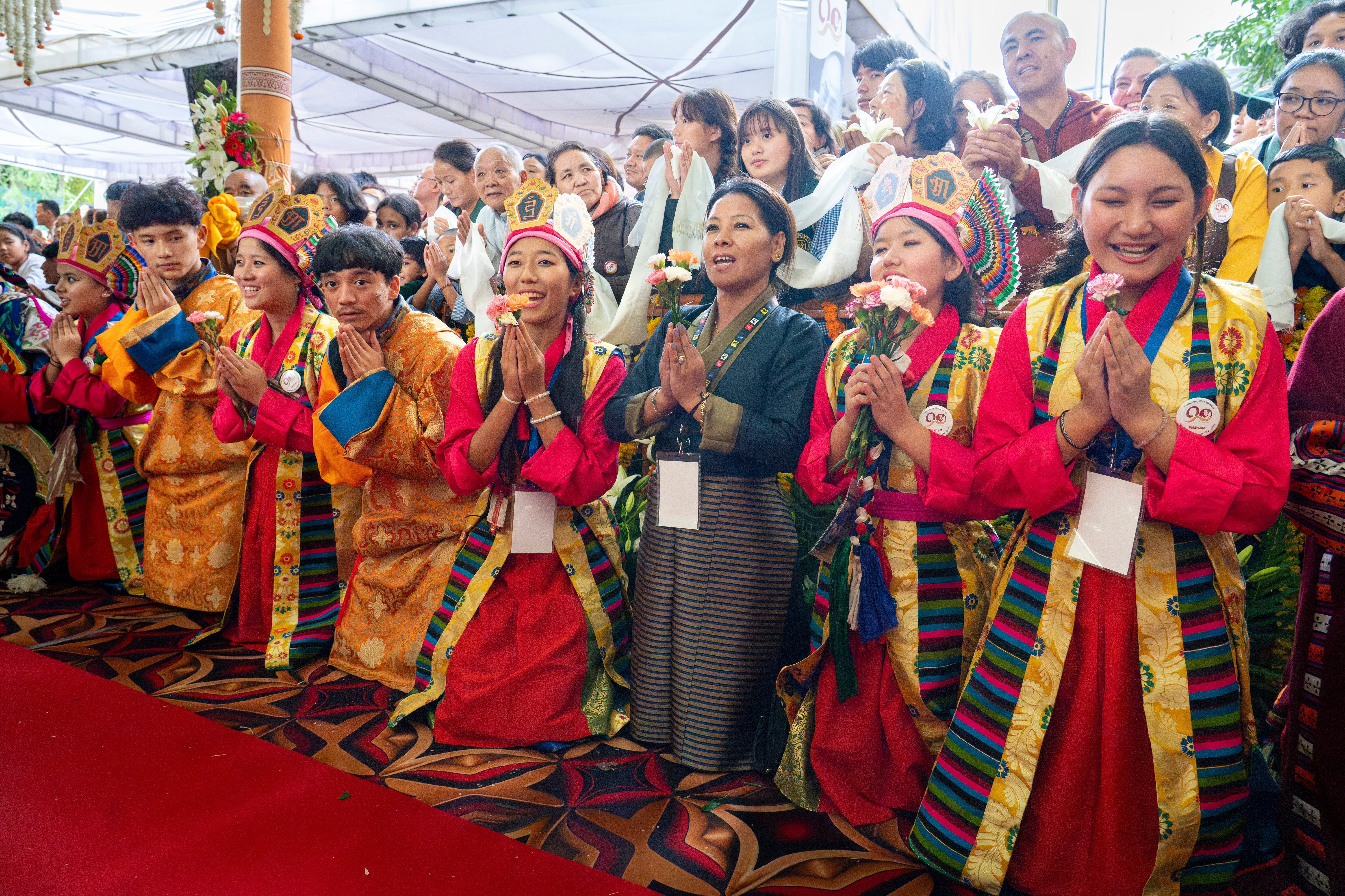 Exiled Tibetans in traditional costumes sing 'Happy Birthday' for their spiritual leader the Dalai Lama, unseen, as he leaves after attending his 90th birthday celebration