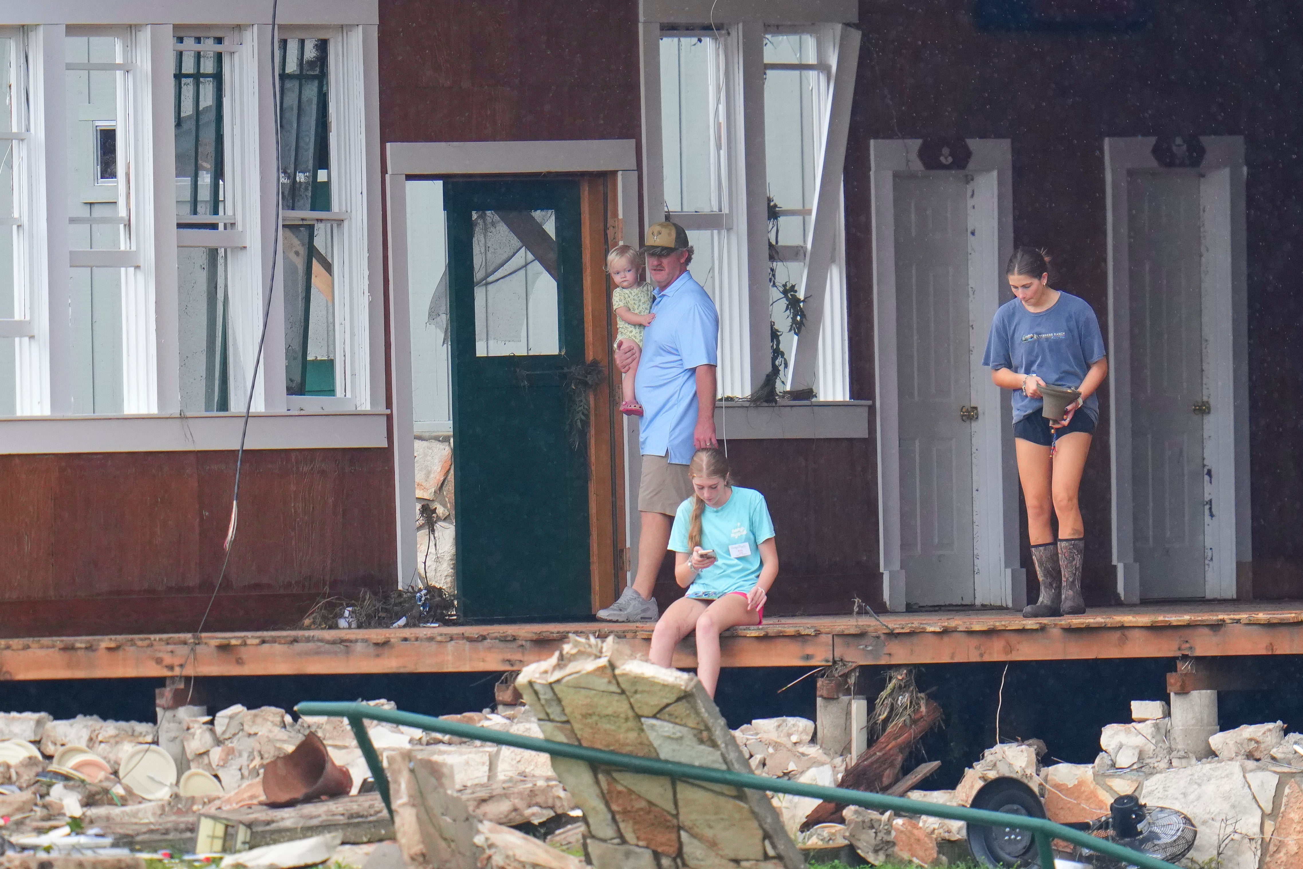 A person salvages a bell from the main building at Camp Mystic along the banks of the Guadalupe River after a flash flood swept through the area Sunday, July 6, 2025, in Hunt, Texas. (AP Photo/Julio Cortez)