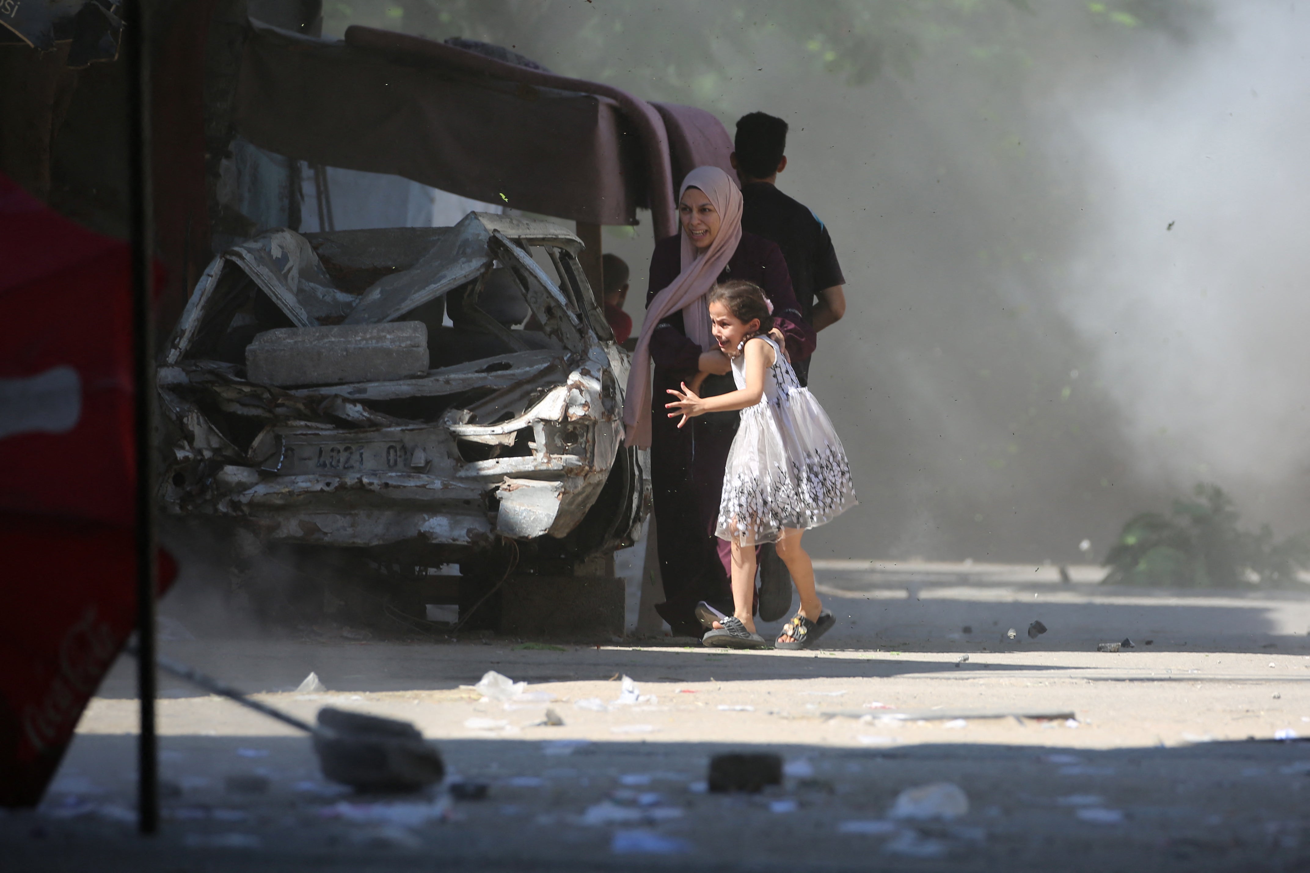 A mother and her daughter rush for cover during an Israeli strike in Al-Bureij camp in the central Gaza Strip