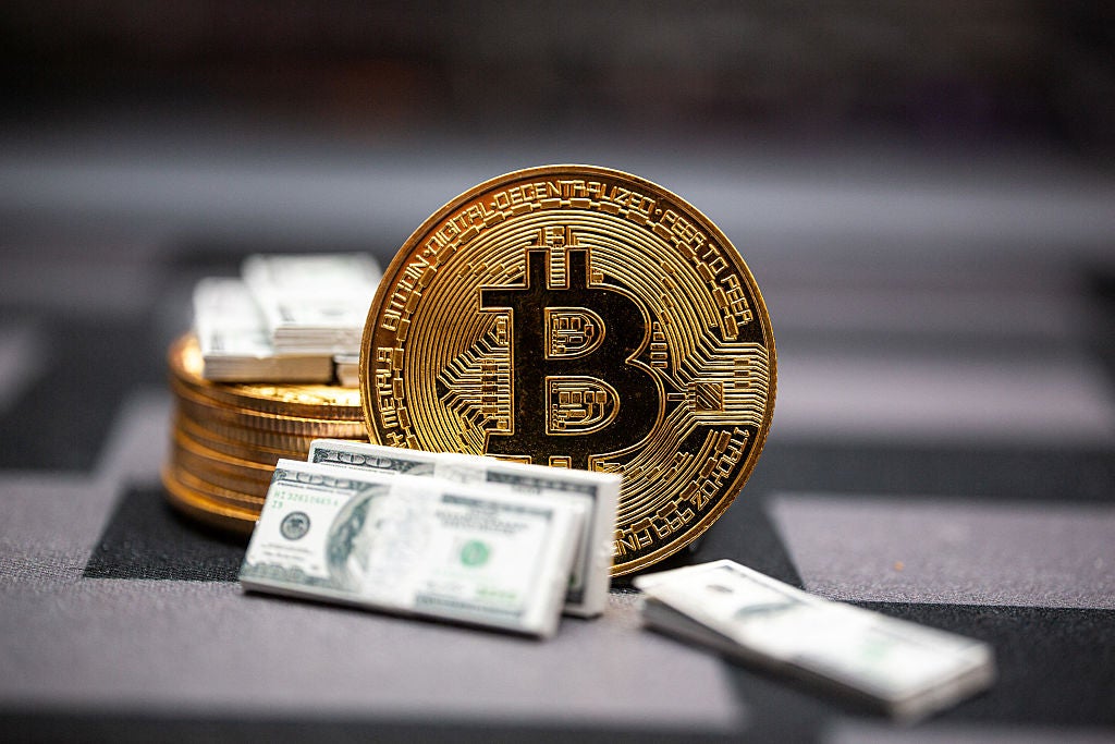 A bitcoin token is displayed next to fake bundles of US dollar bills in Clermont-Ferrand France on 14 June 2025