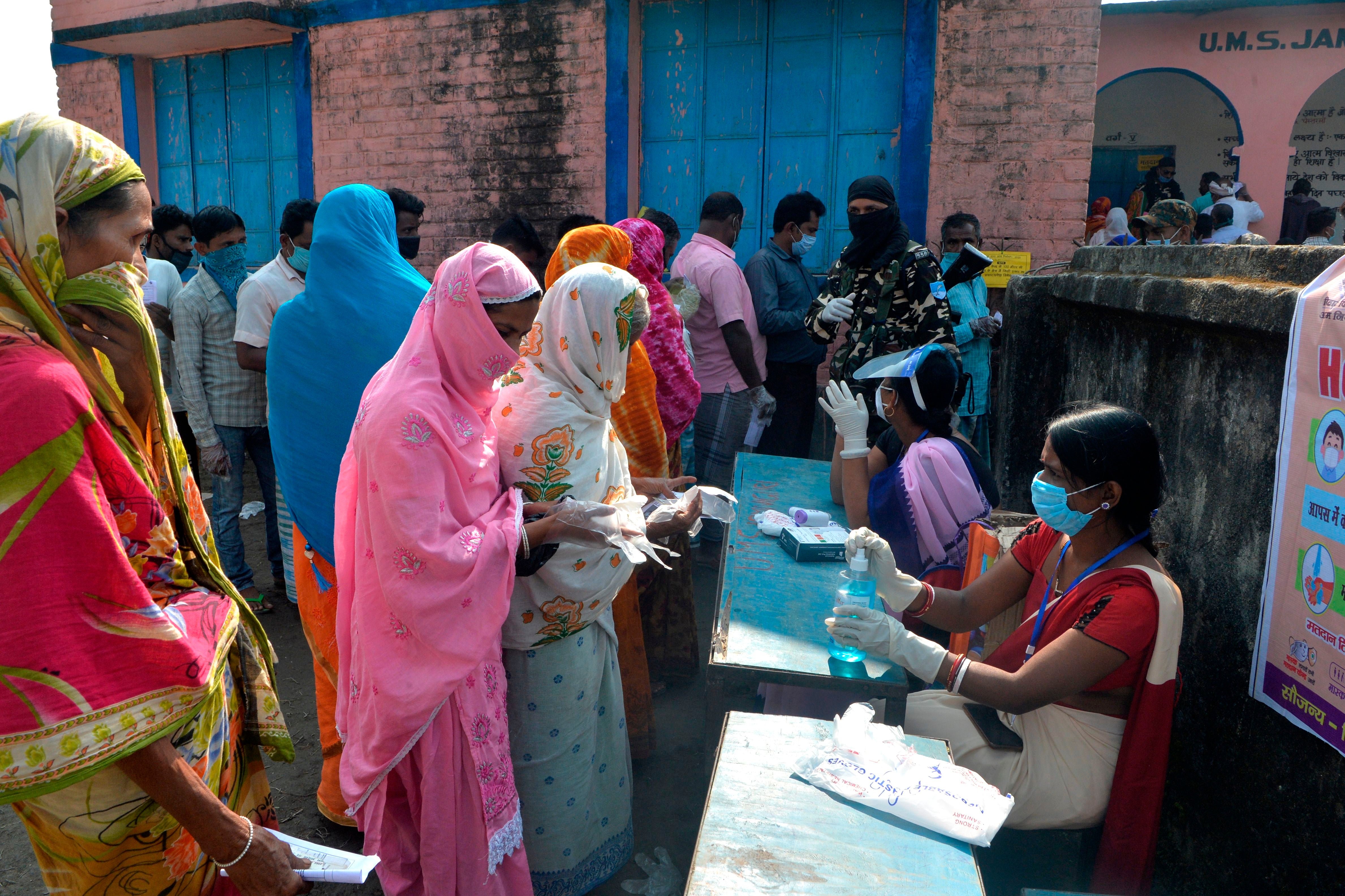 Voters queue up to cast their ballots at a polling station during the last phase of Bihar state assembly elections in Thakurganj on 7 November 2020