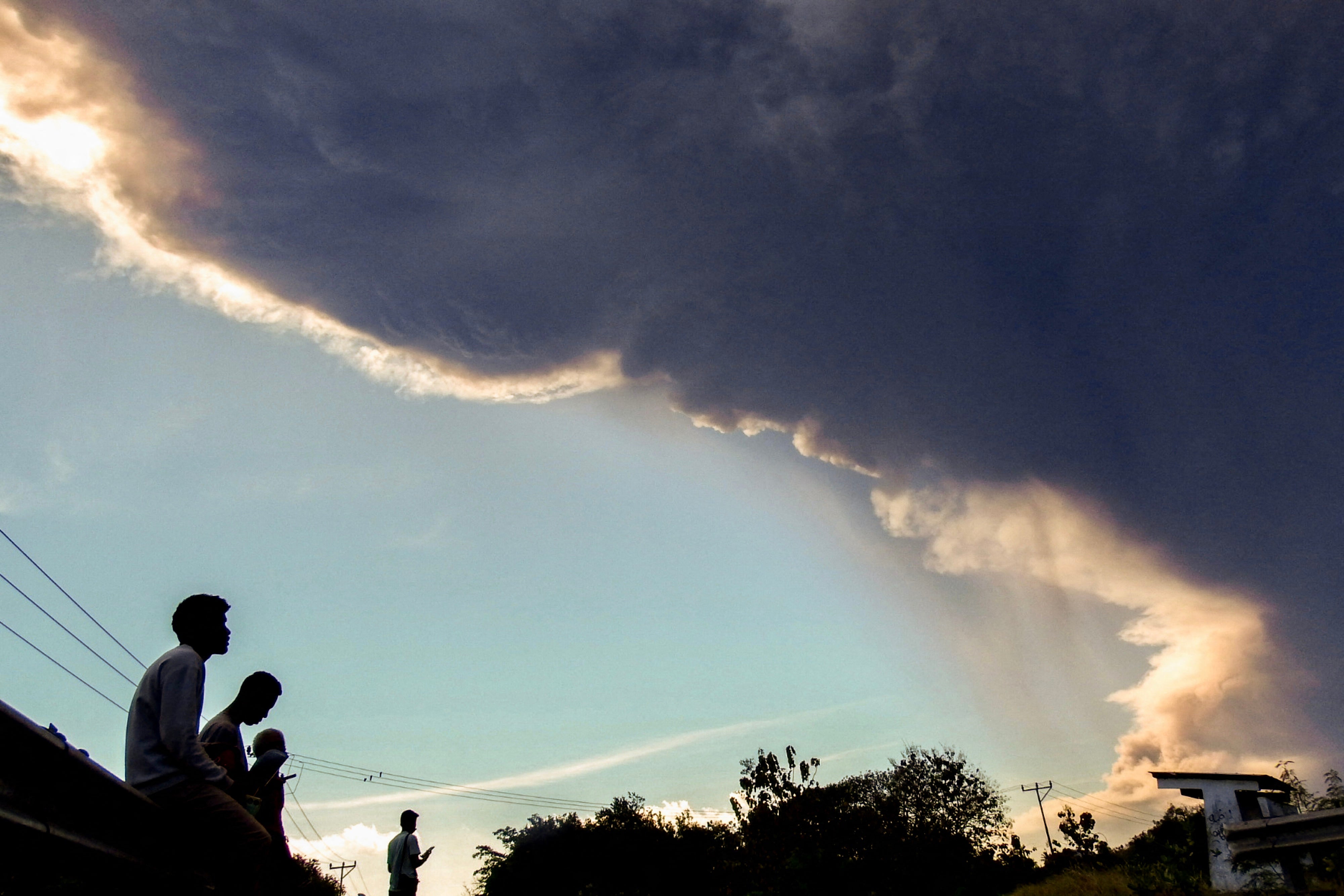 Villagers observe Mount Lewotobi Laki-laki as it erupts, as seen from Nangahale village in Sikka, East Nusa Tenggara on 7 July 2025