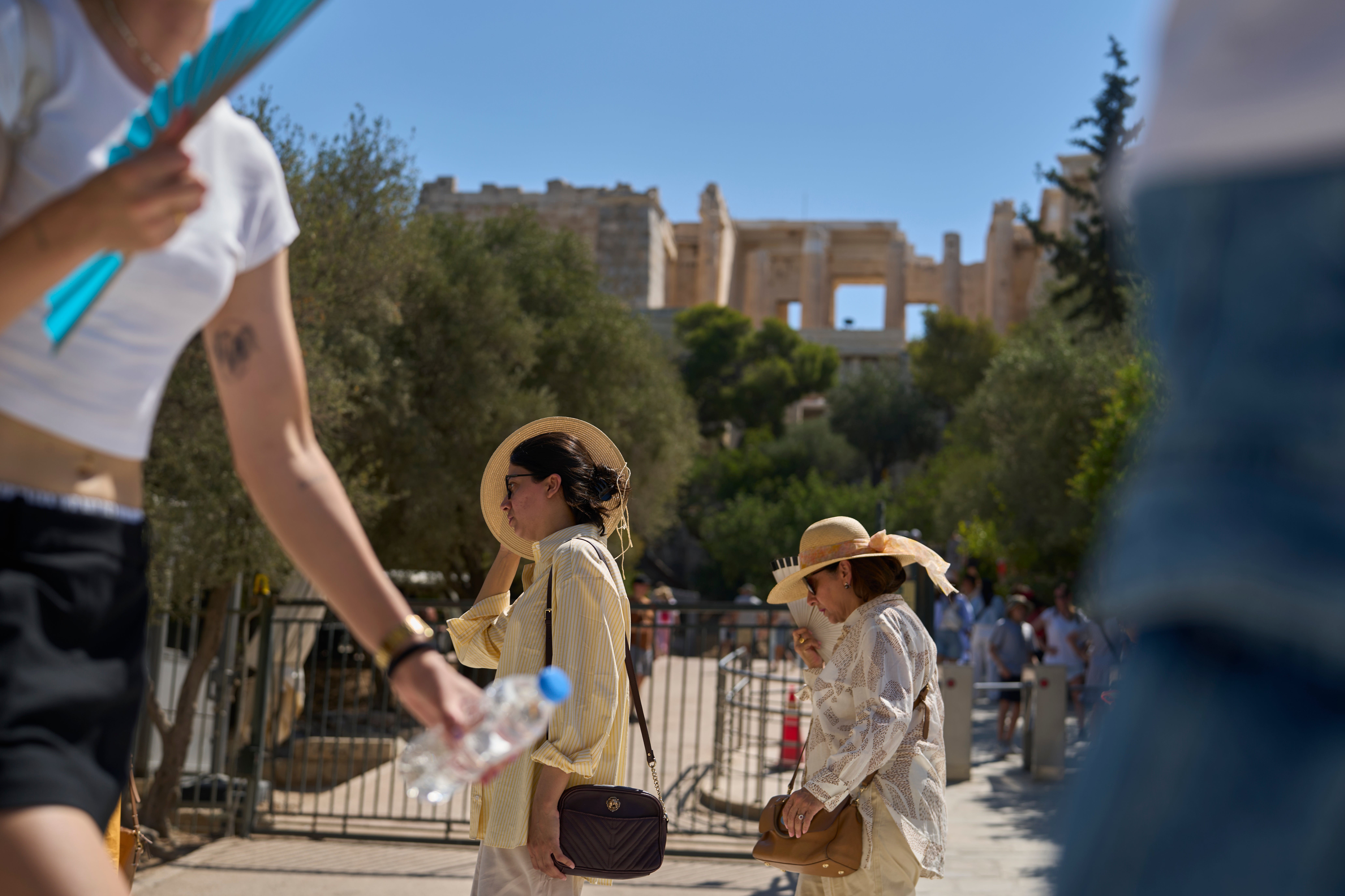 Tourist walk outside the Acropolis of Athens, on Monday, July 7, 2025 while authorities in Greece have imposed mandatory work stoppages in parts of the country where temperatures are expected to exceed 40 degrees Celsius (104 Fahrenheit) (AP Photo/Petros Giannakouris)