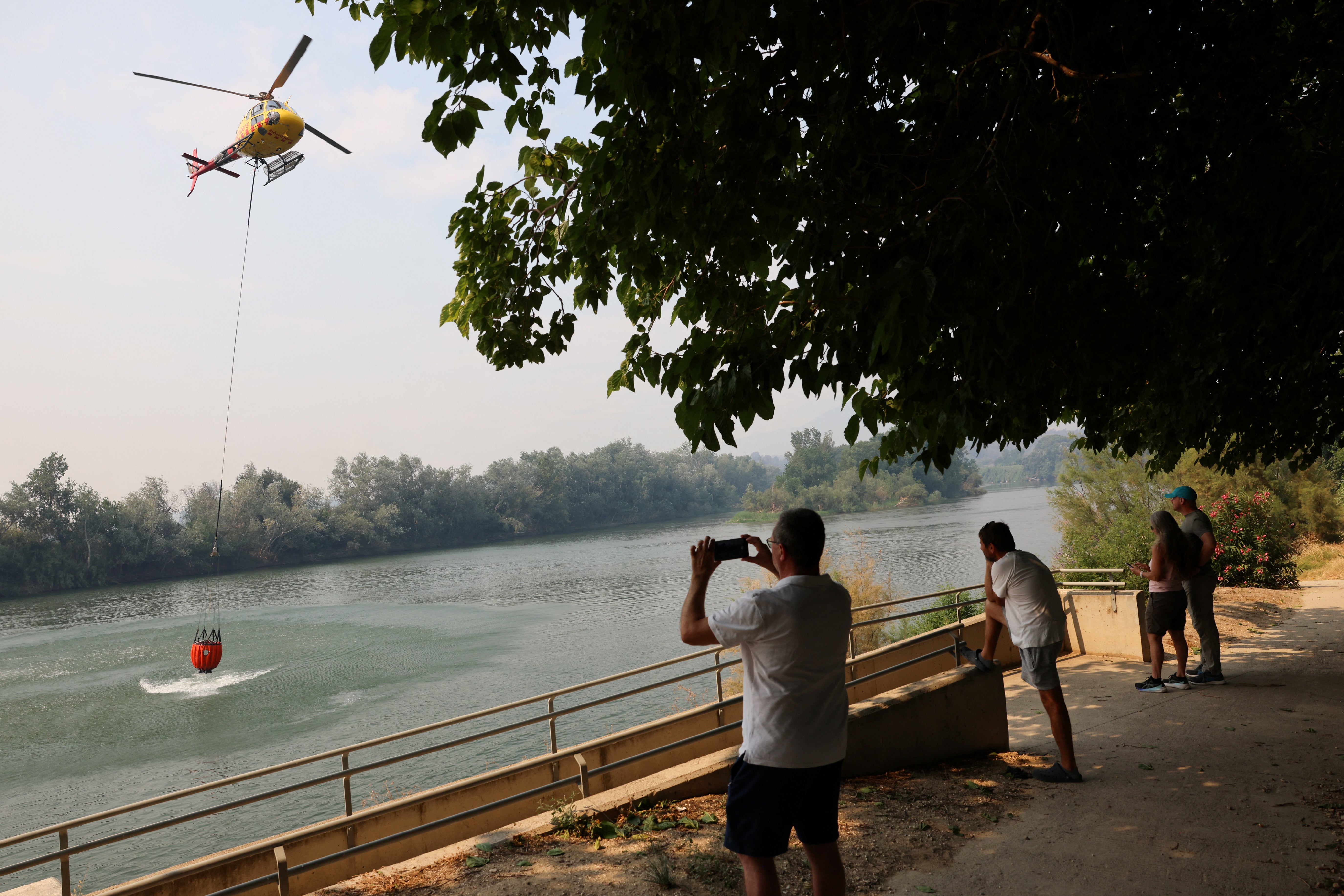 A helicopter flies to help extinguish a fire in Xerta