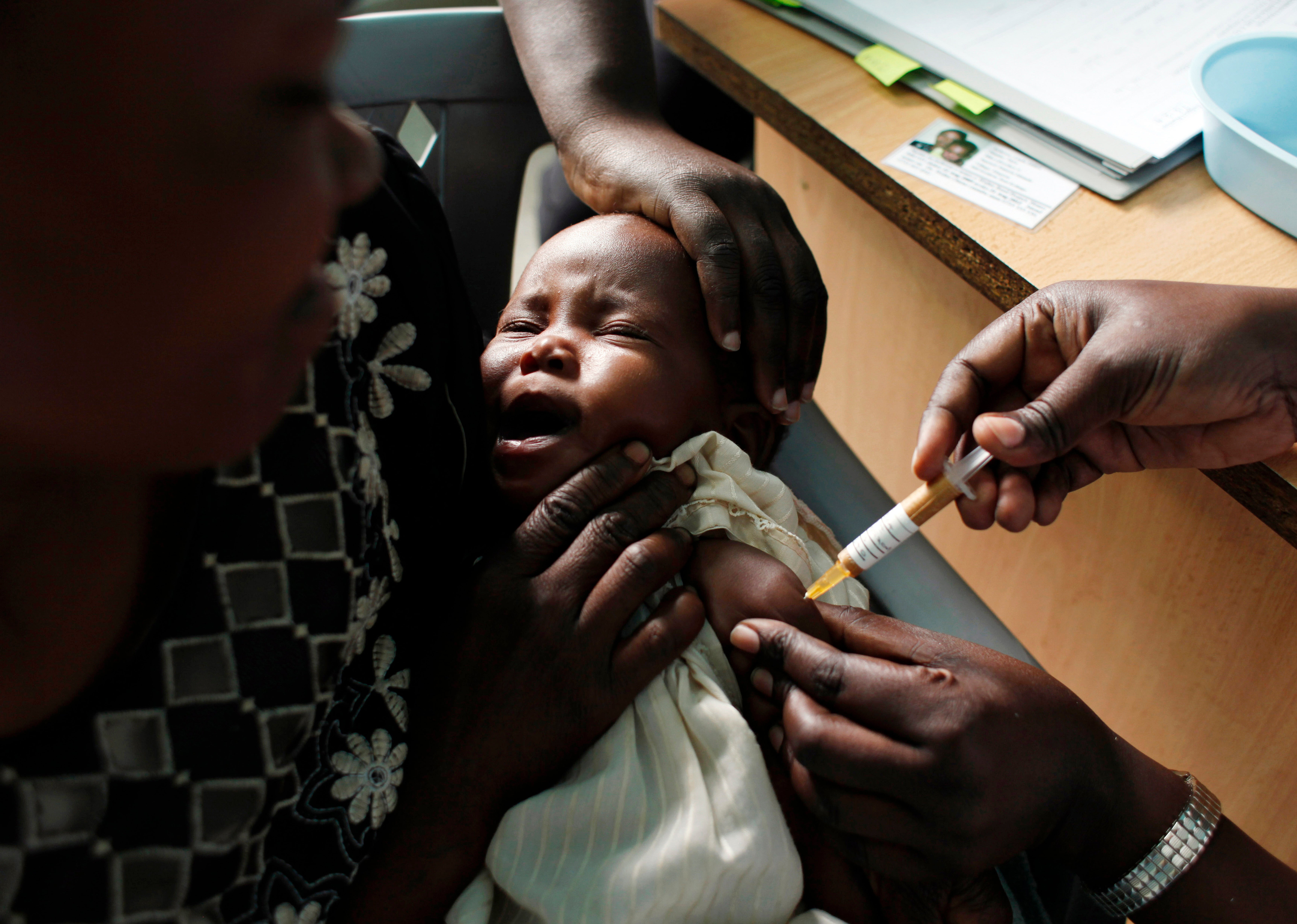 A mother holds her baby receiving a new malaria vaccine as part of a trial at the Walter Reed Project Research Center in Kombewa in Western Kenya on Oct. 30, 2009. (AP Photo/Karel Prinsloo, File)