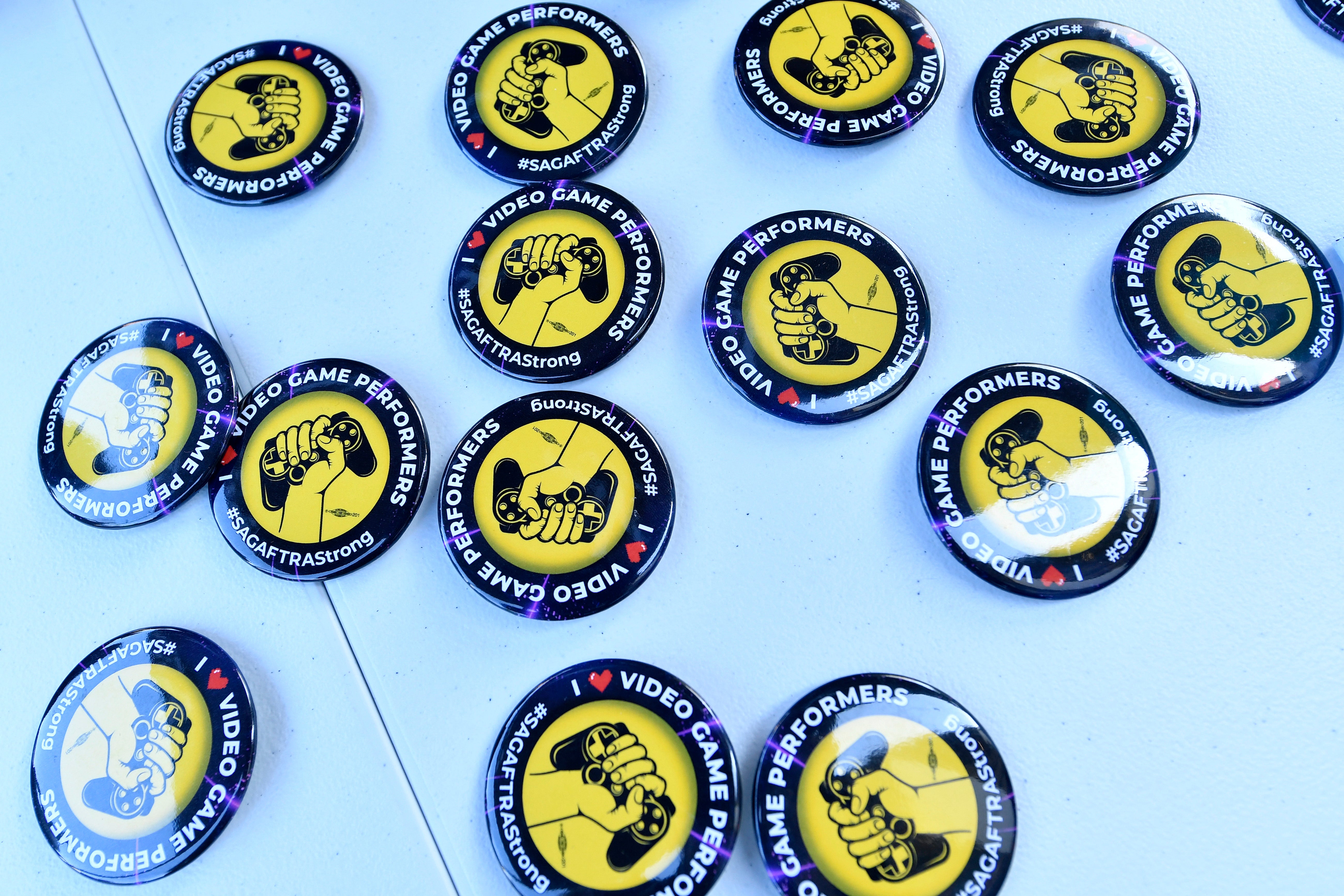 Strike buttons are displayed as SAG-AFTRA union video game performers strike outside Warner Bros. Games