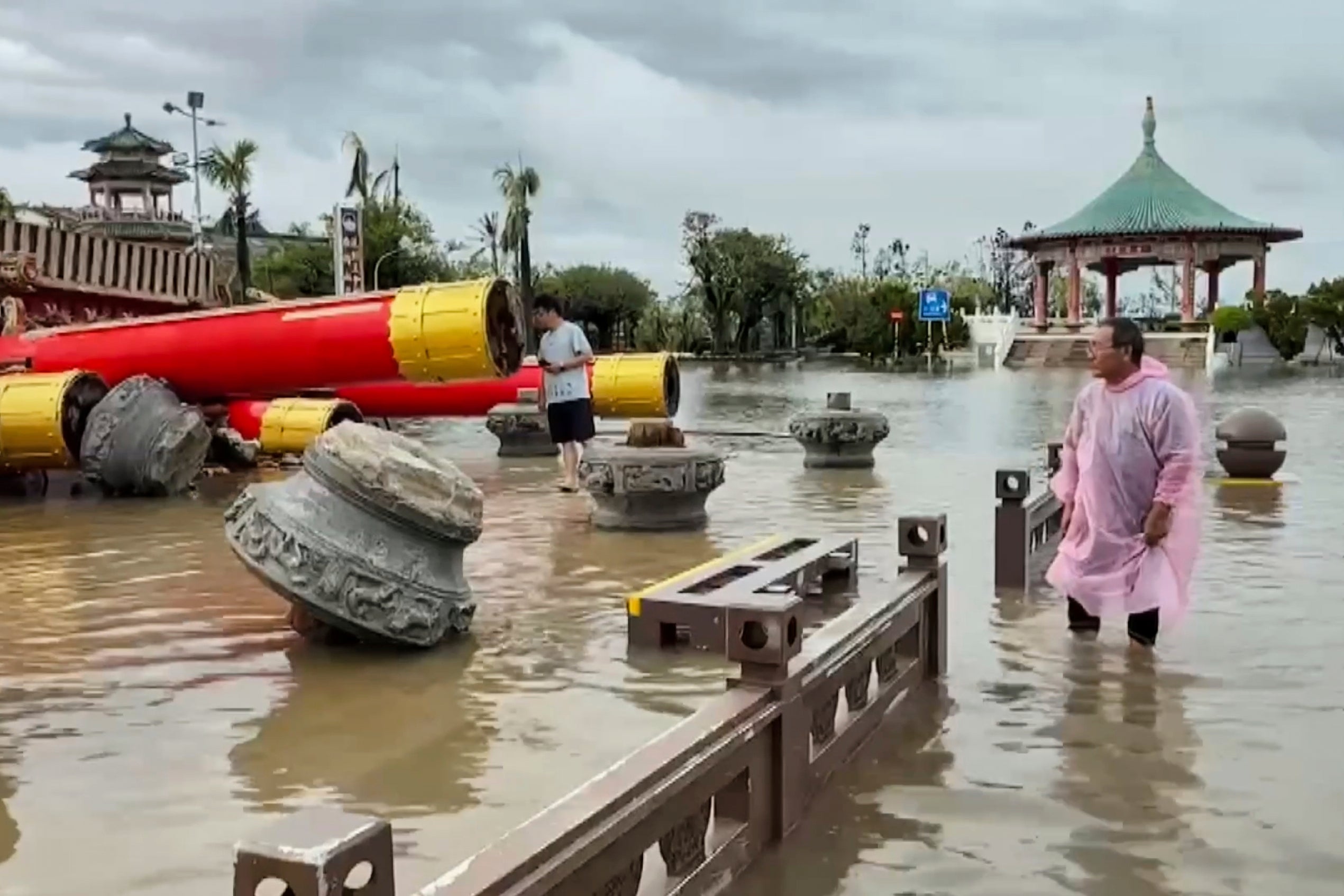 Residents look at the collapsed temple structures submerged in floodwaters