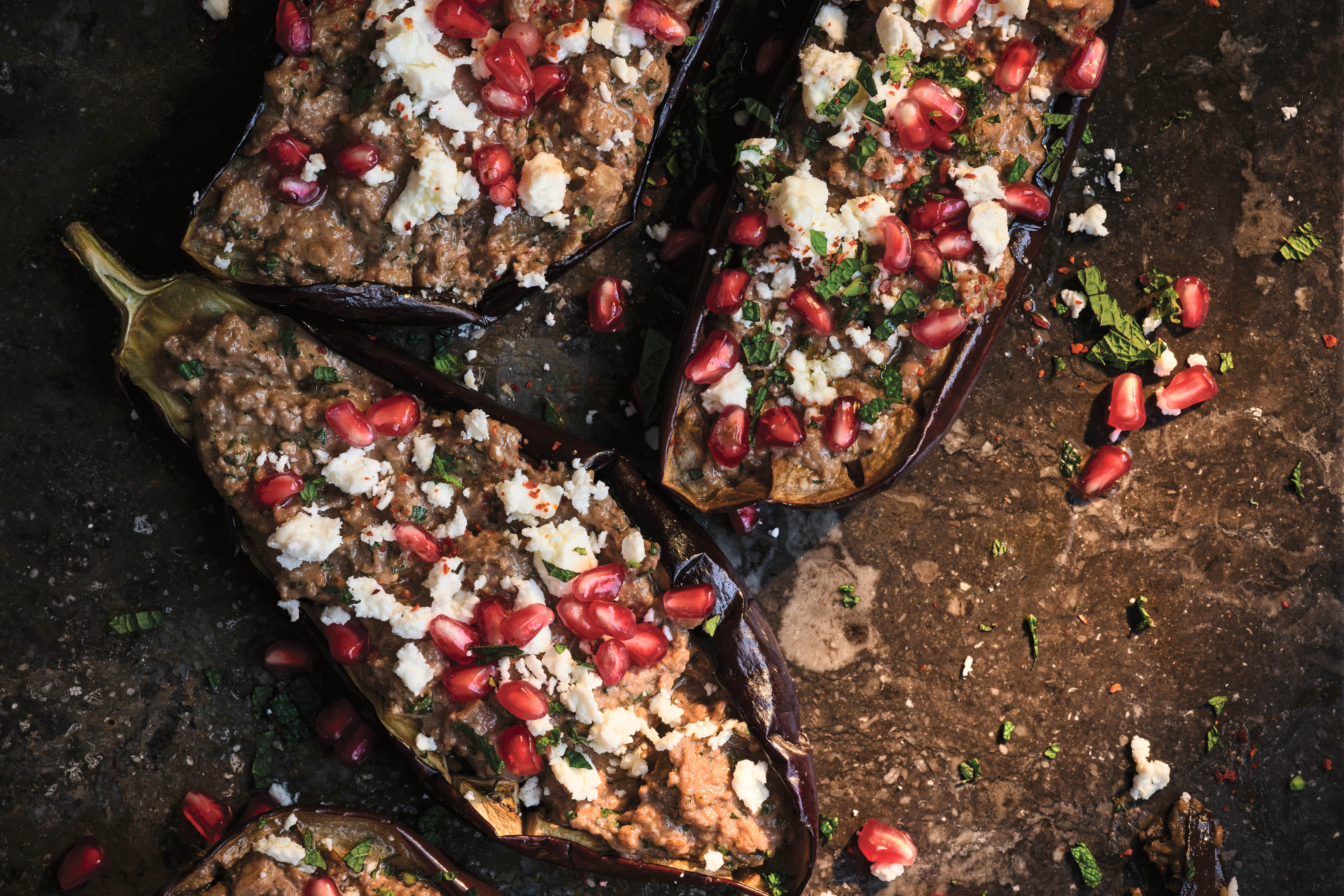 Roasted aubergines are filled with a punchy mix of herbs, walnuts and pomegranate molasses, then topped with feta and jewels of pomegranate for a true Persian showstopper