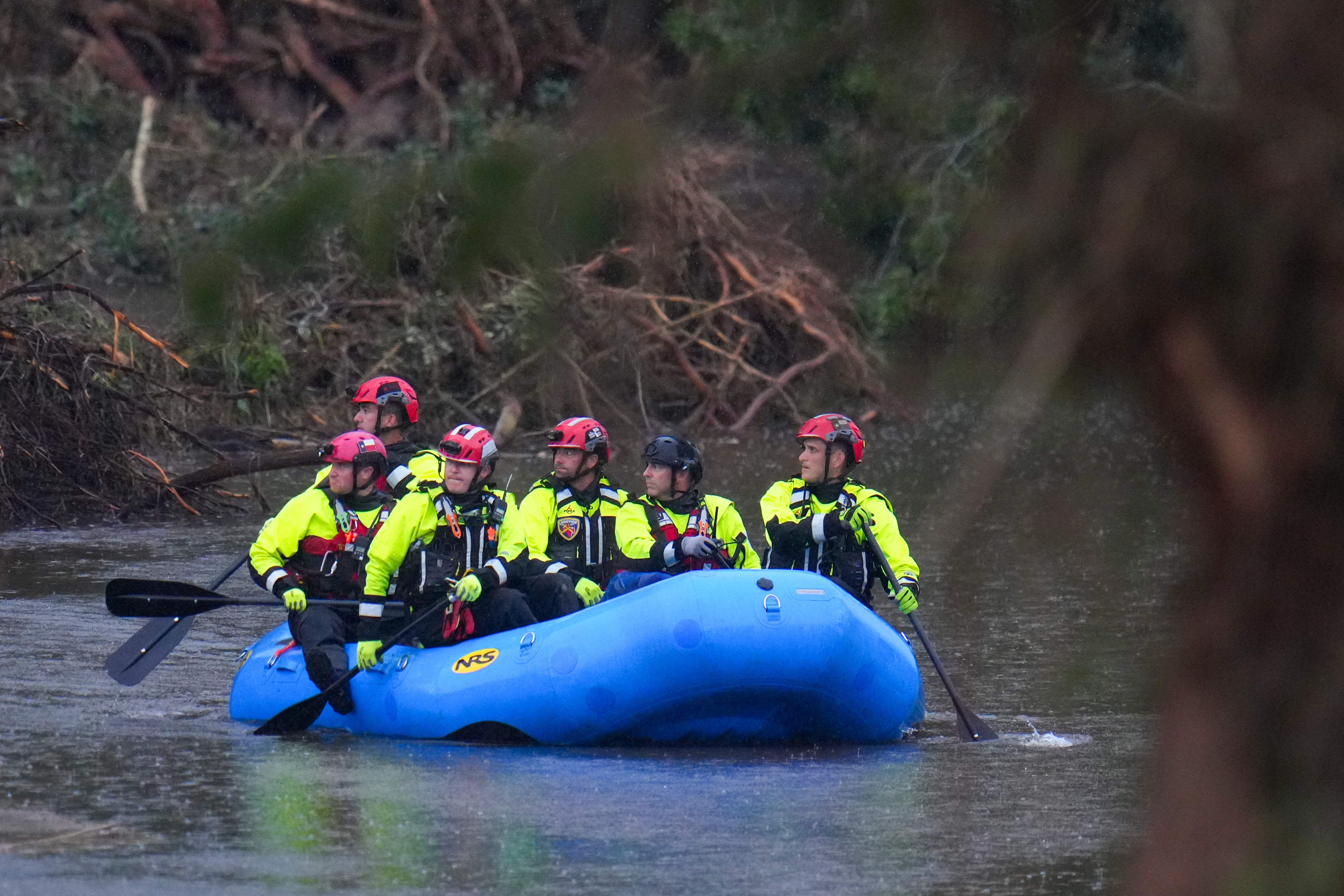 Officials ride a boat as they arrive to assist with a recovery effort at Camp Mystic along the Guadalupe River