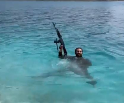 In the video, a man is armed even while swimming