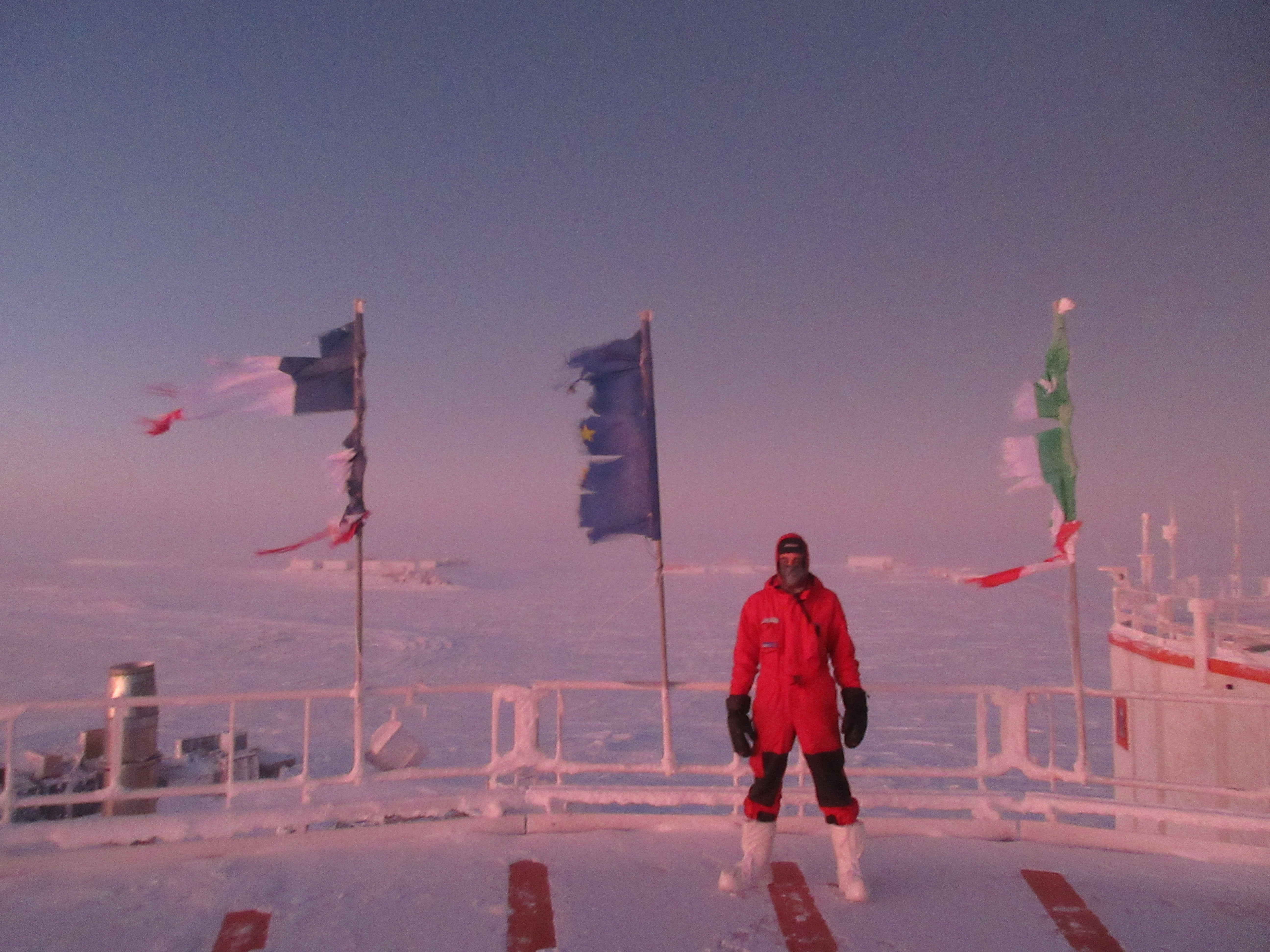Cyprien Verseux stands next to the same flags, now damaged by wear and tear, at the end of the polar night after 9 months of wintering over