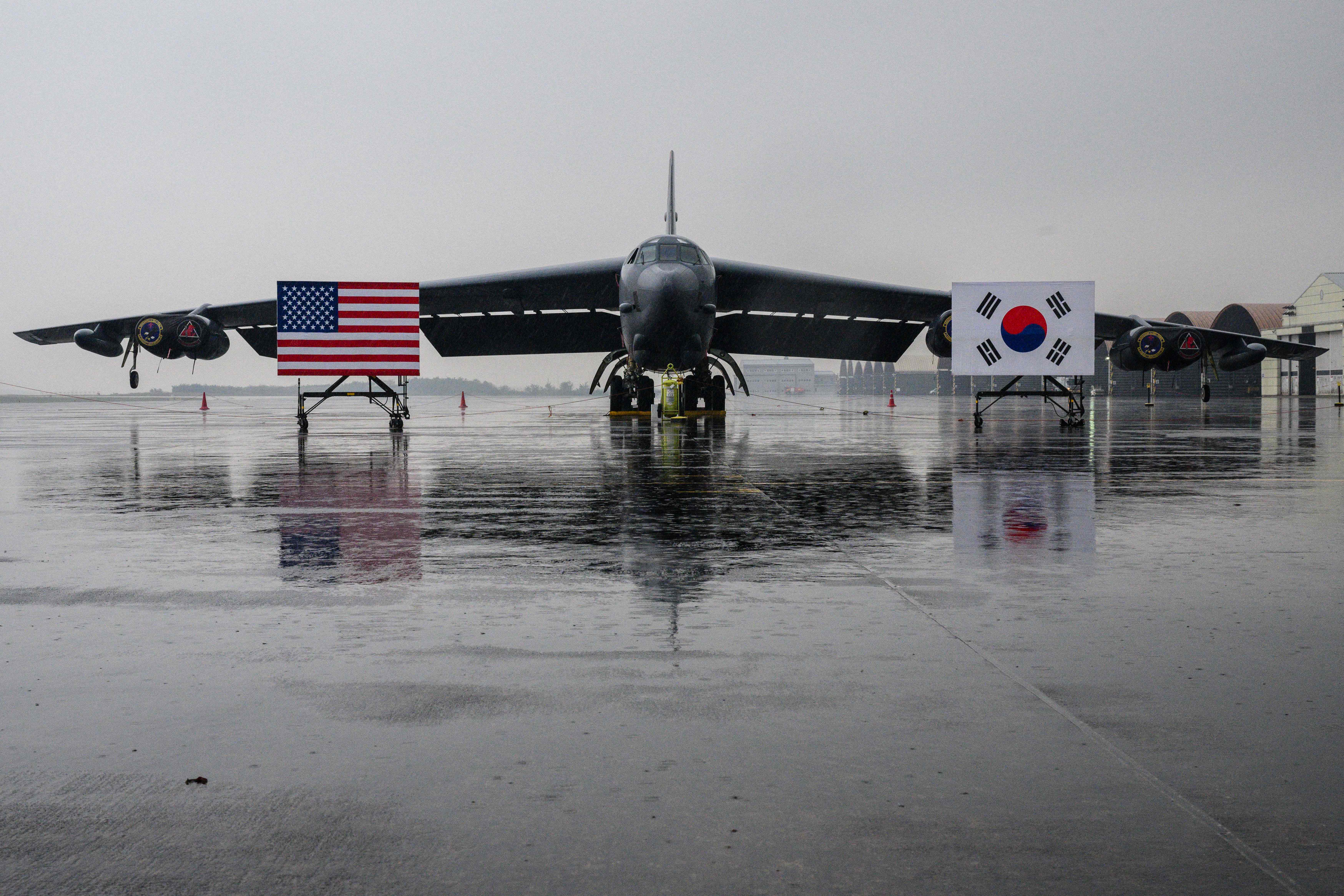 National flags of the US and South Korea are displayed in front of a strategic bomber at a South Korean Air Force base in 2023