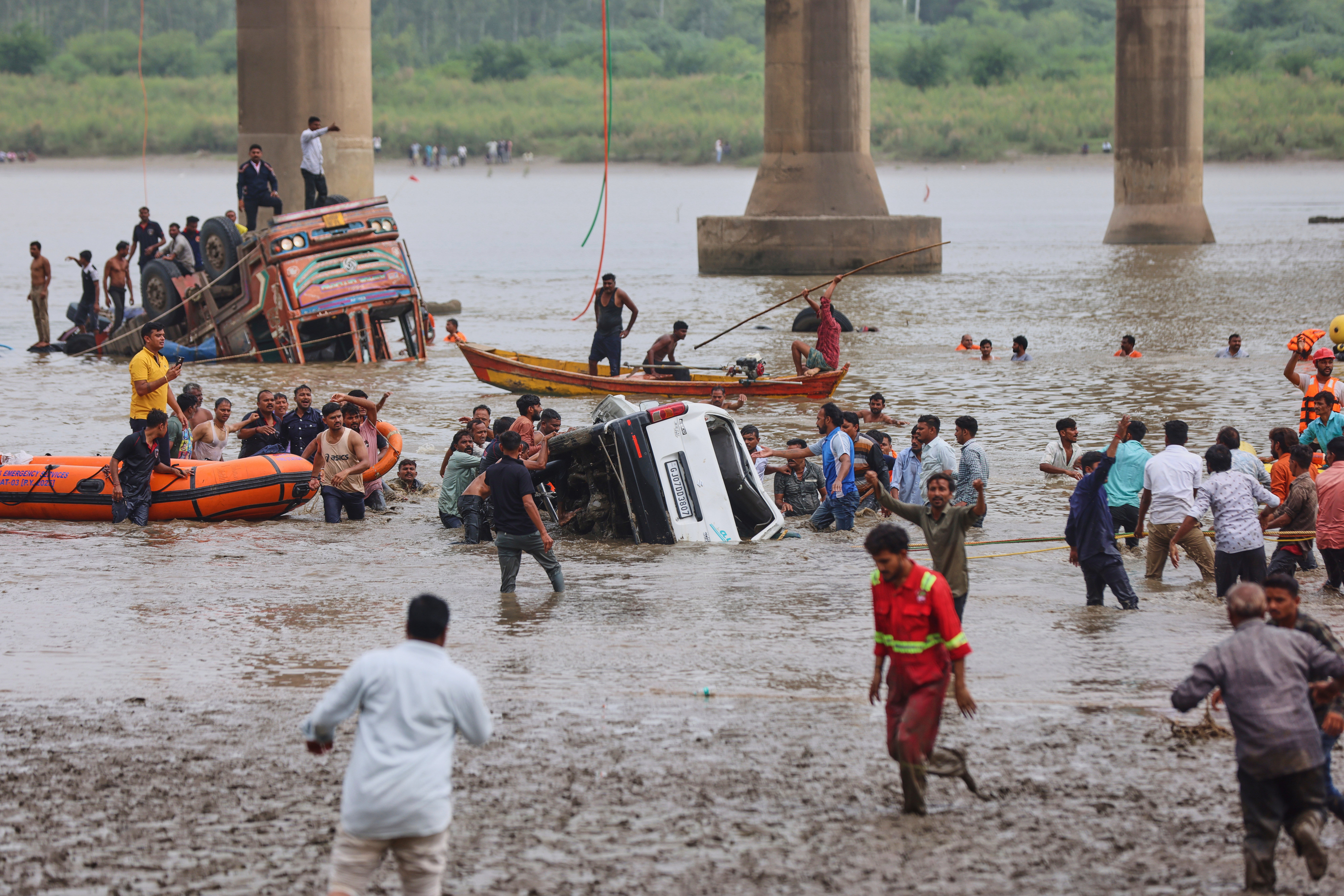 Rescuers and locals look for survivors after several vehicles fell into a river