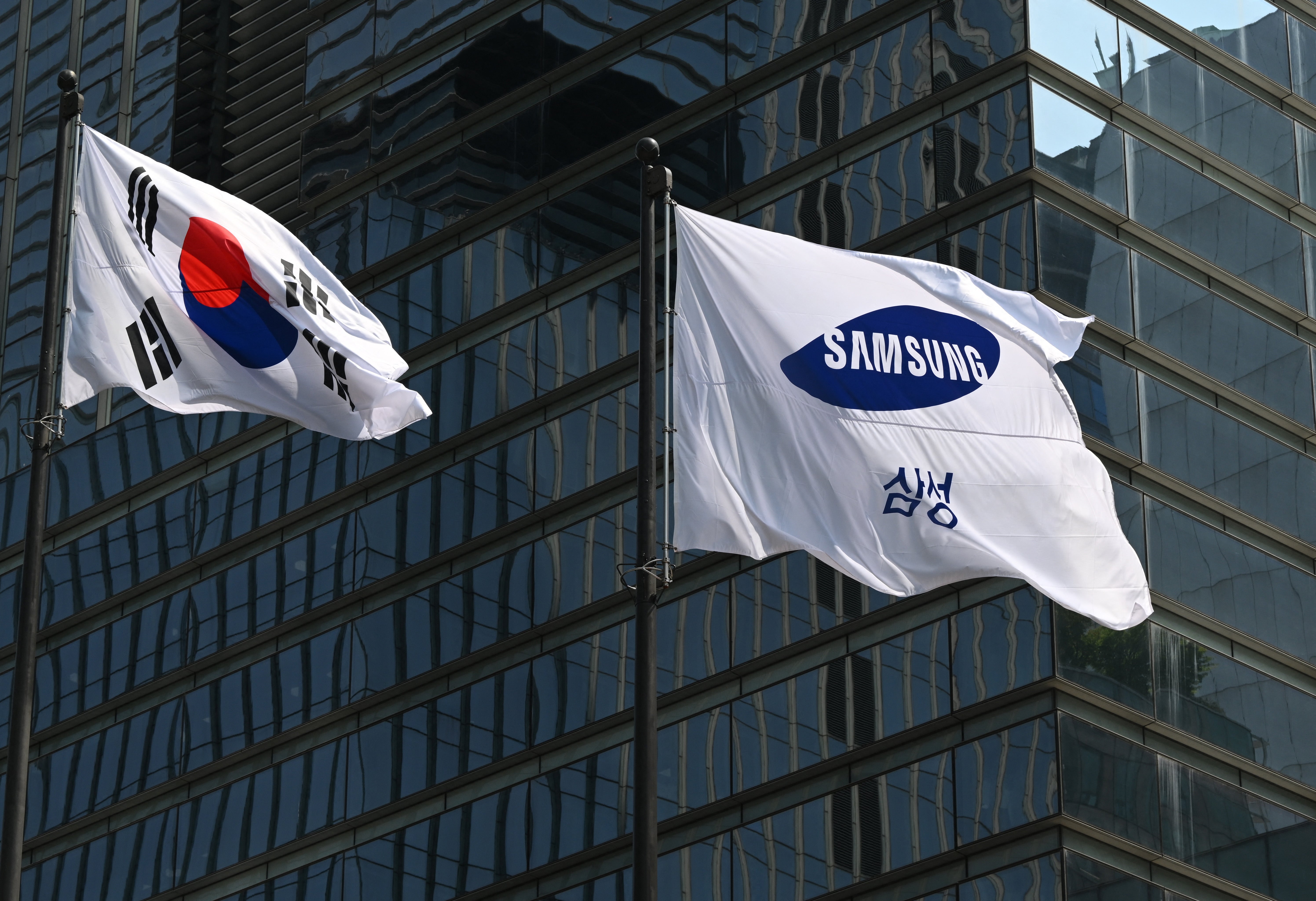 The flags of South Korea (L) and Samsung (R) flutter outside the company's Seocho building in Seoul on 8 July 2025