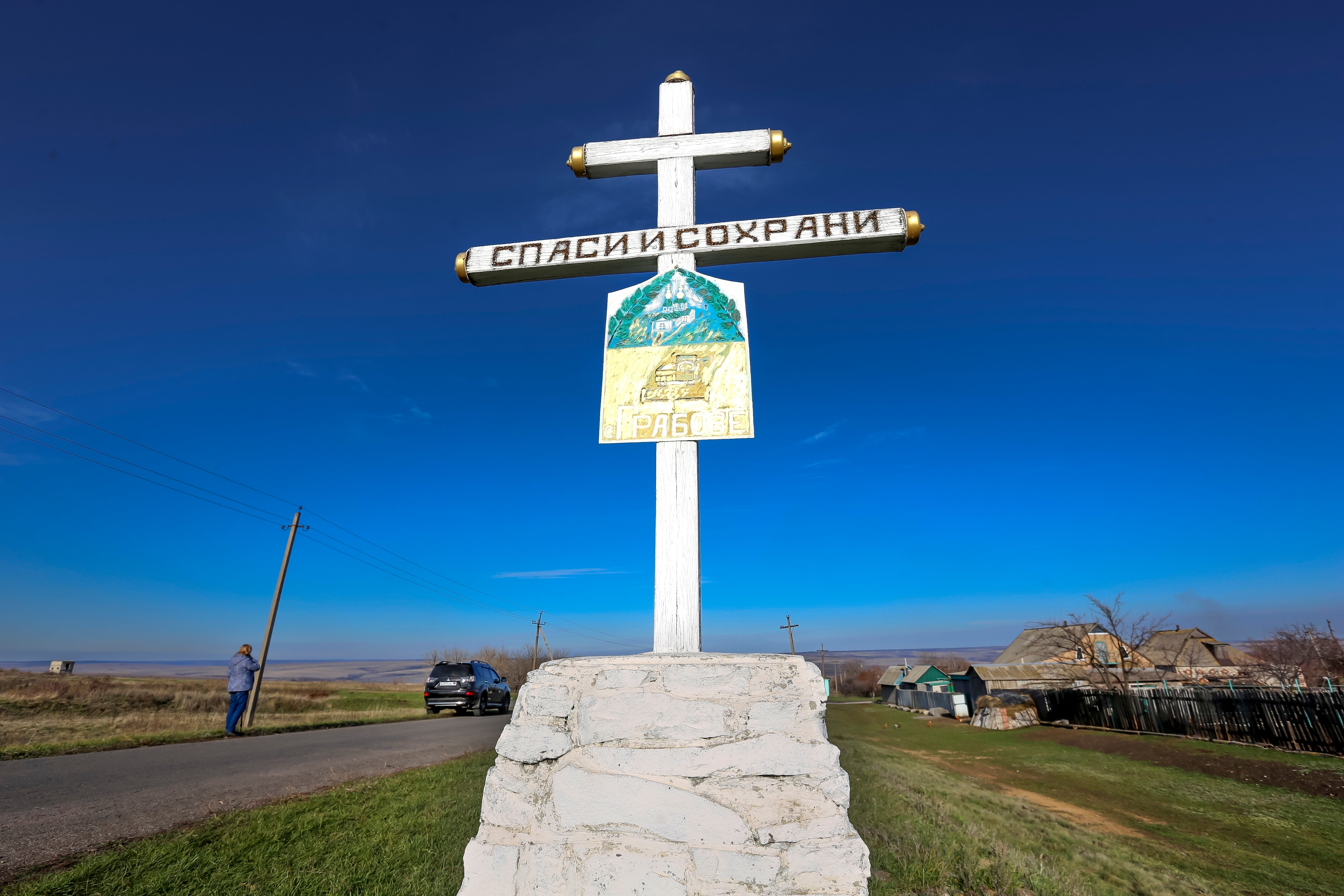 An Orthodox cross with a sign reading Save and Guard, is seen with a memorial to the victims of the Malaysian Airlines MH17 plane crash.