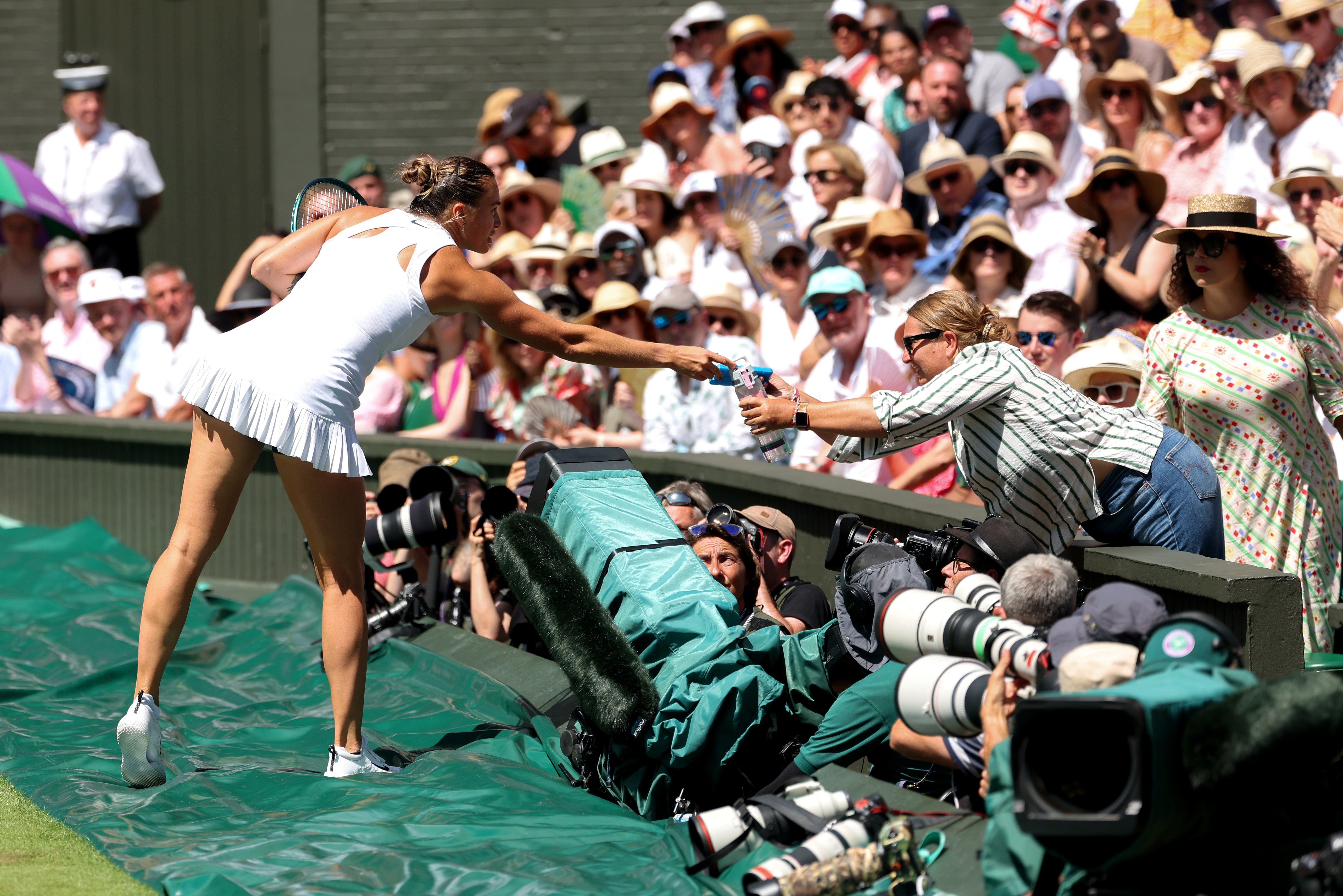 Aryna Sabalenka handing water to be passed back to a fan who had fainted