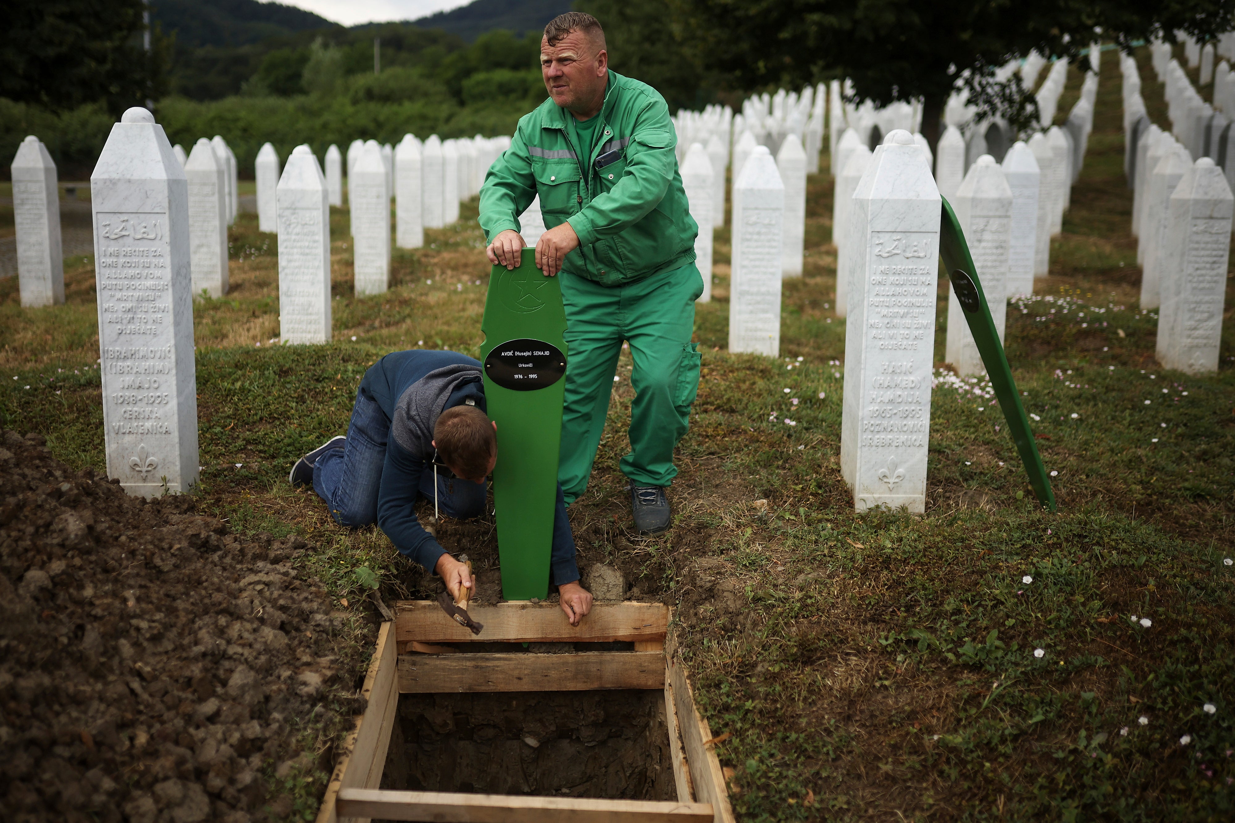 Cemetery workers prepare graves for a mass burial of seven newly identified victims of the 1995 Srebrenica genocide in Potocari, Bosnia
