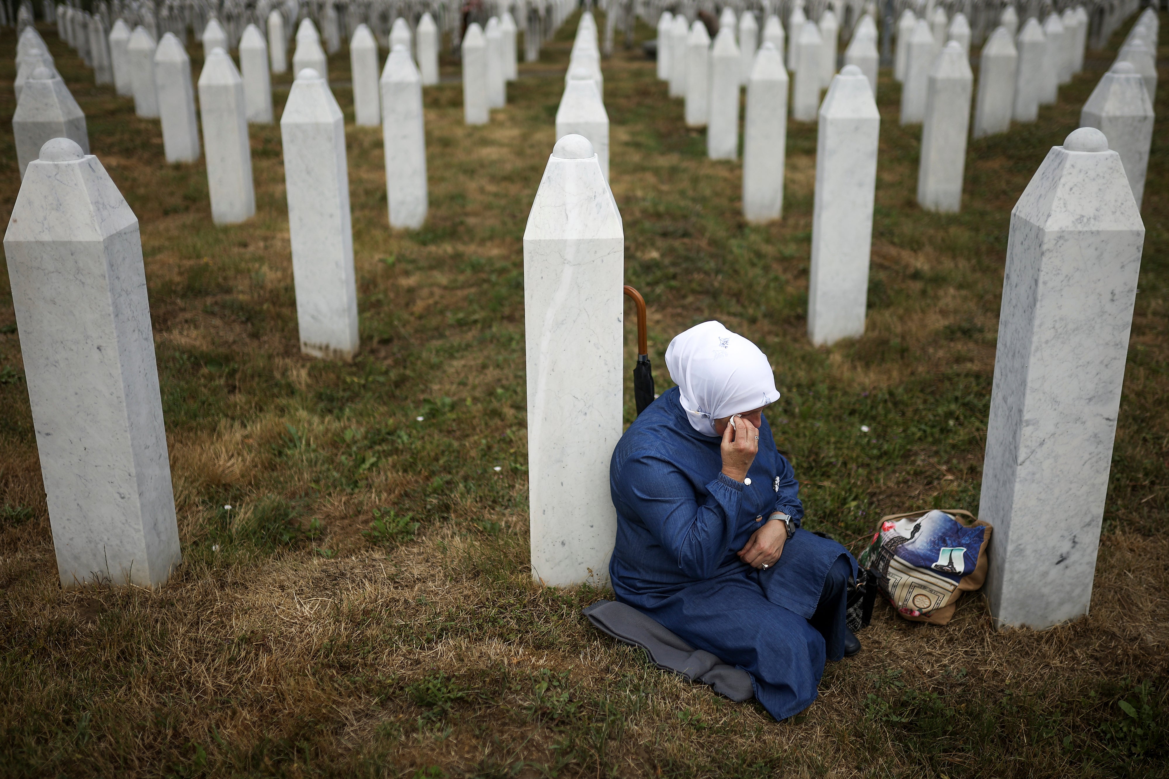 A Bosnian Muslim woman mourns next to the grave of her relative, a victim of the Srebrenica genocide