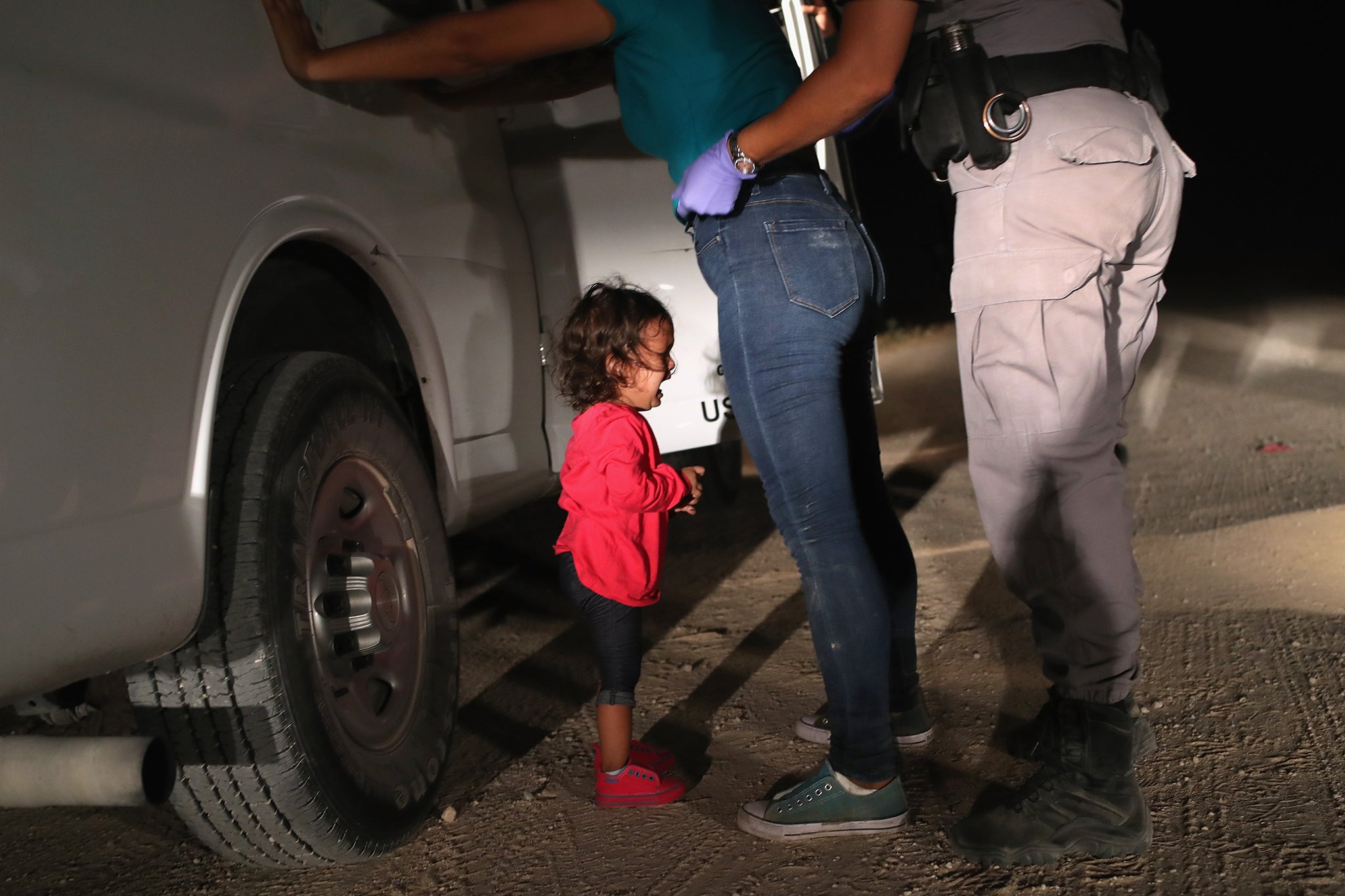 A two-year-old Honduran asylum seeker cries as her mother is searched and detained near the U.S.-Mexico border in 2018, under the first Trump administration. They were detained by U.S. Border Patrol agents before being sent to a processing center for possible separation. Children must be able to argue their case for asylum in front of a judge.