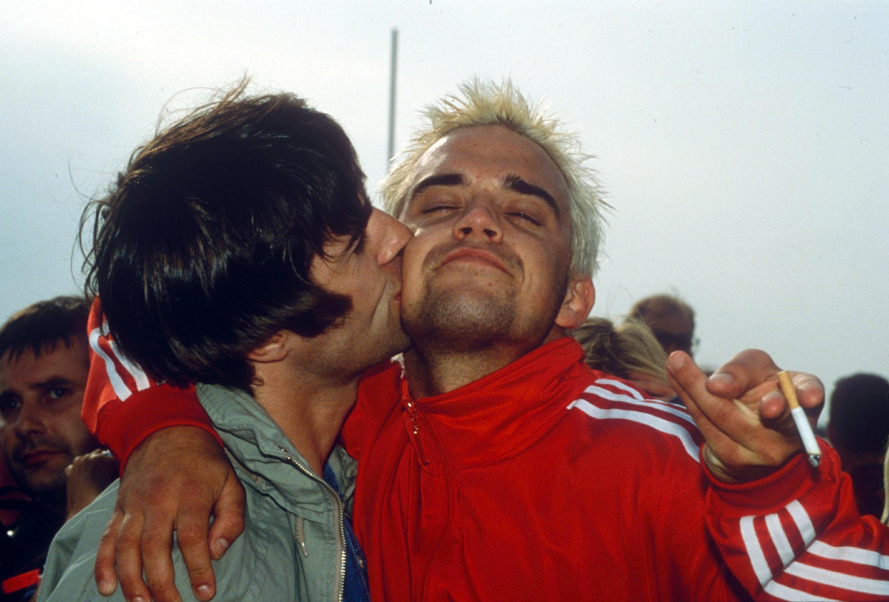 Blondes have more fun: Liam Gallagher plants a smacker on Robbie Williams during the 1995 Glastonbury Festival