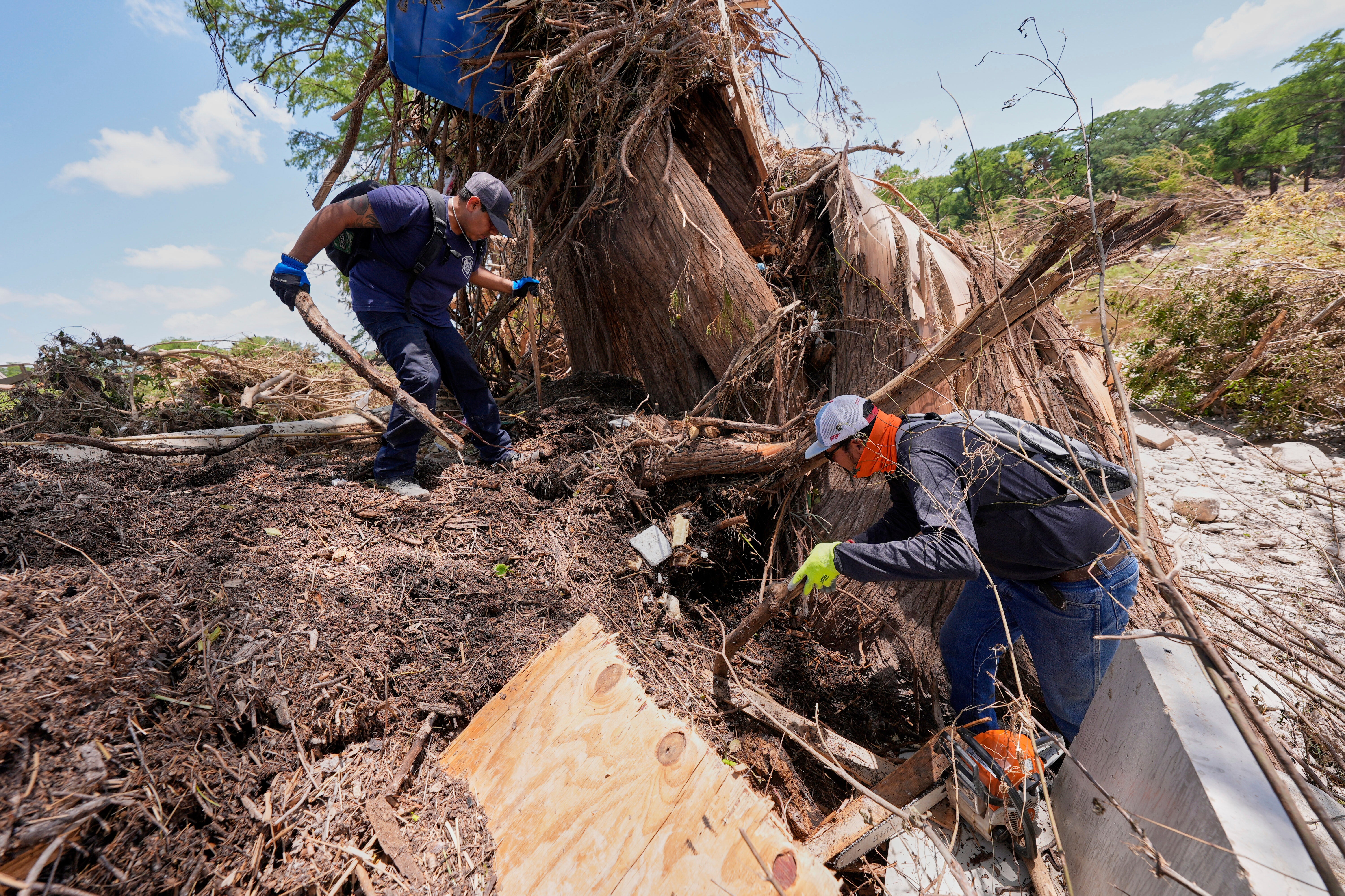 Volunteer Mario Rios, right, and a fellow volunteer search along the bank of the river after flash floods along the Guadalupe River in Kerrville, Texas